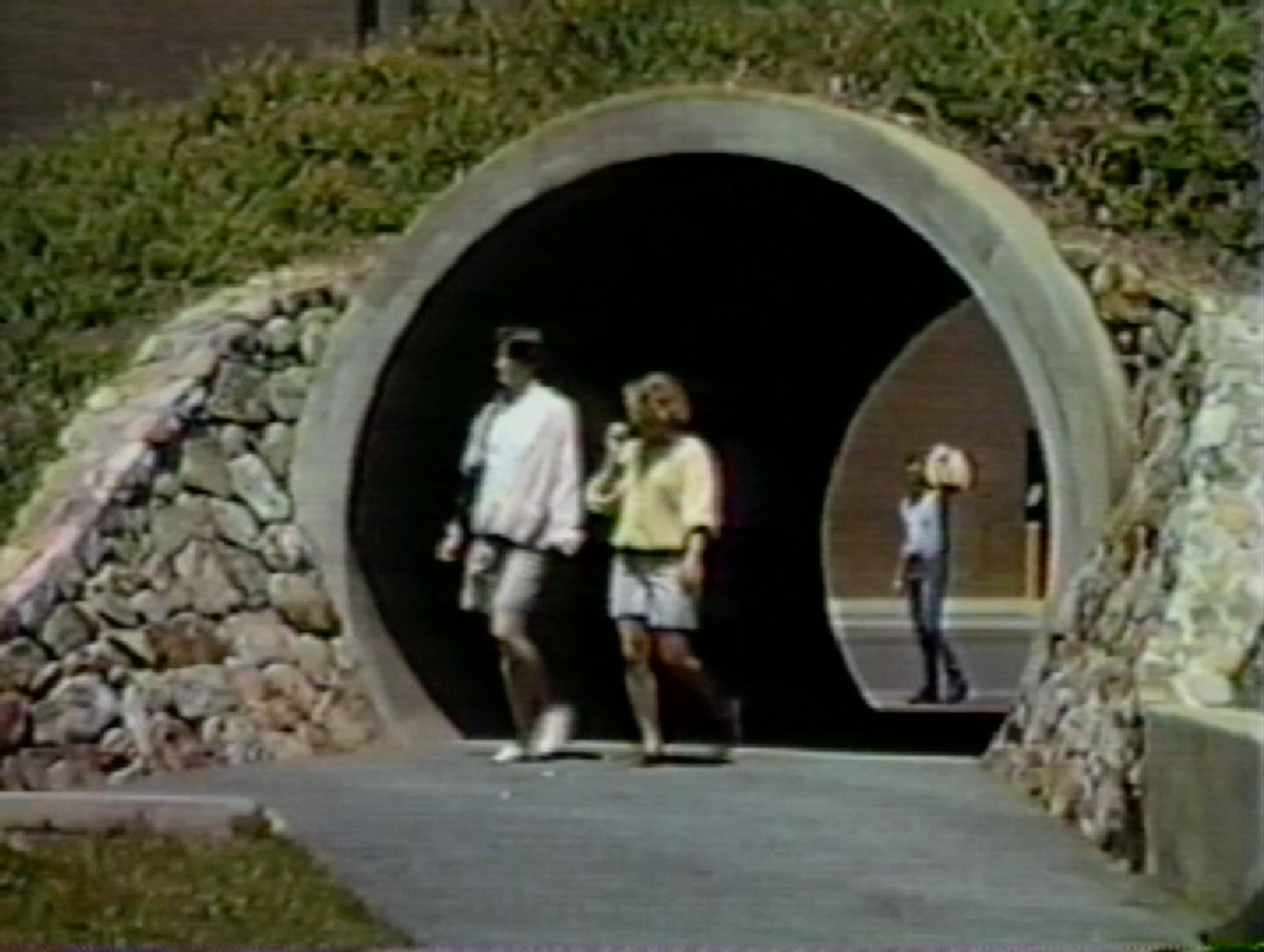 people walking through a large circular tunnel in a hillside