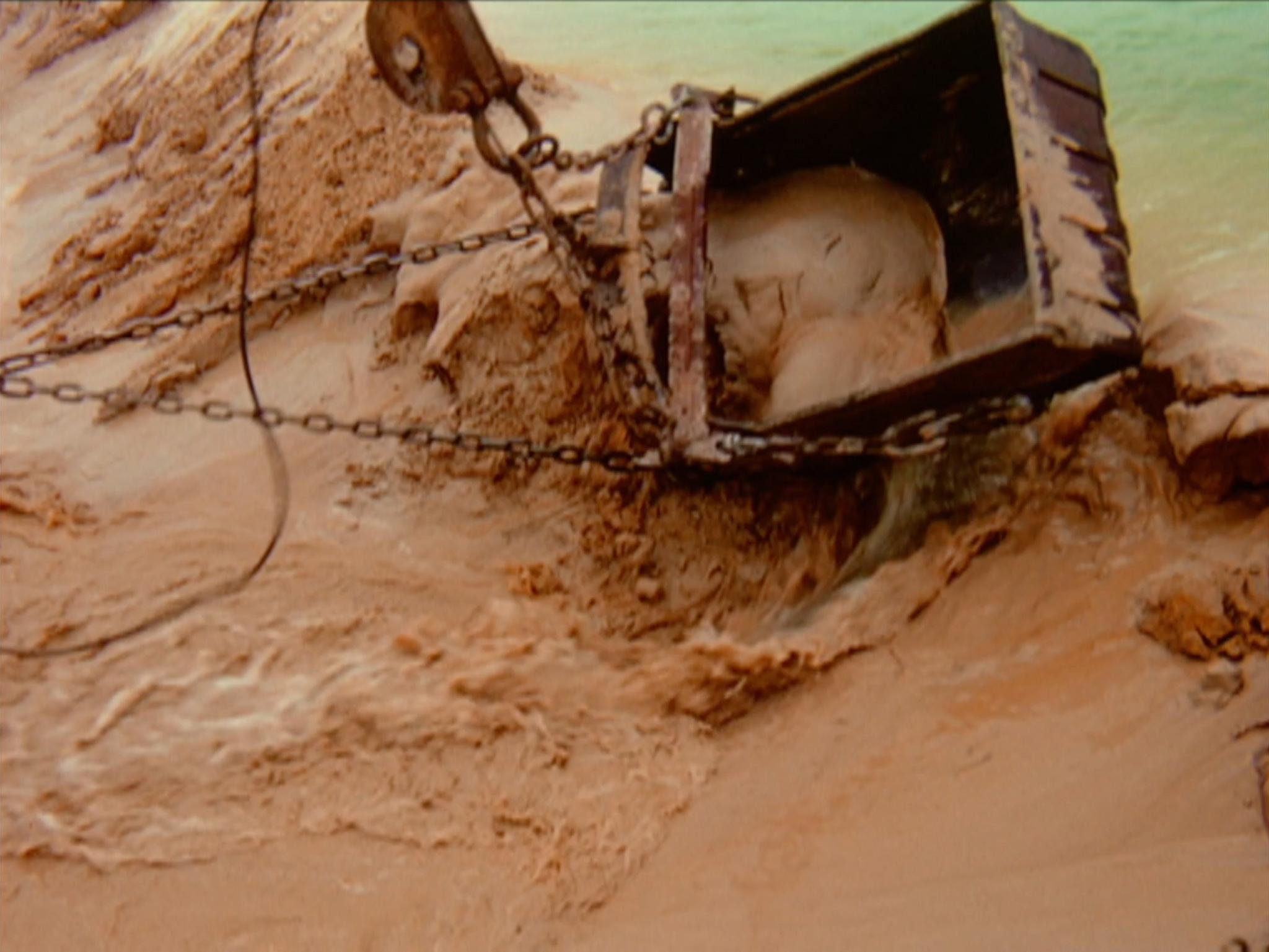 a dragline scooping up earth and water rushes in behind