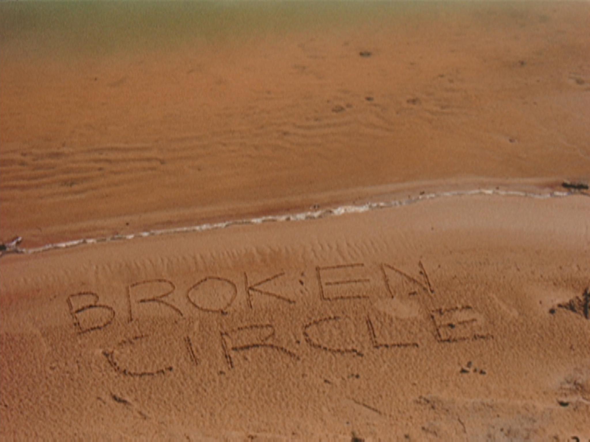 the words Broken Circle are etched into a sandy shore