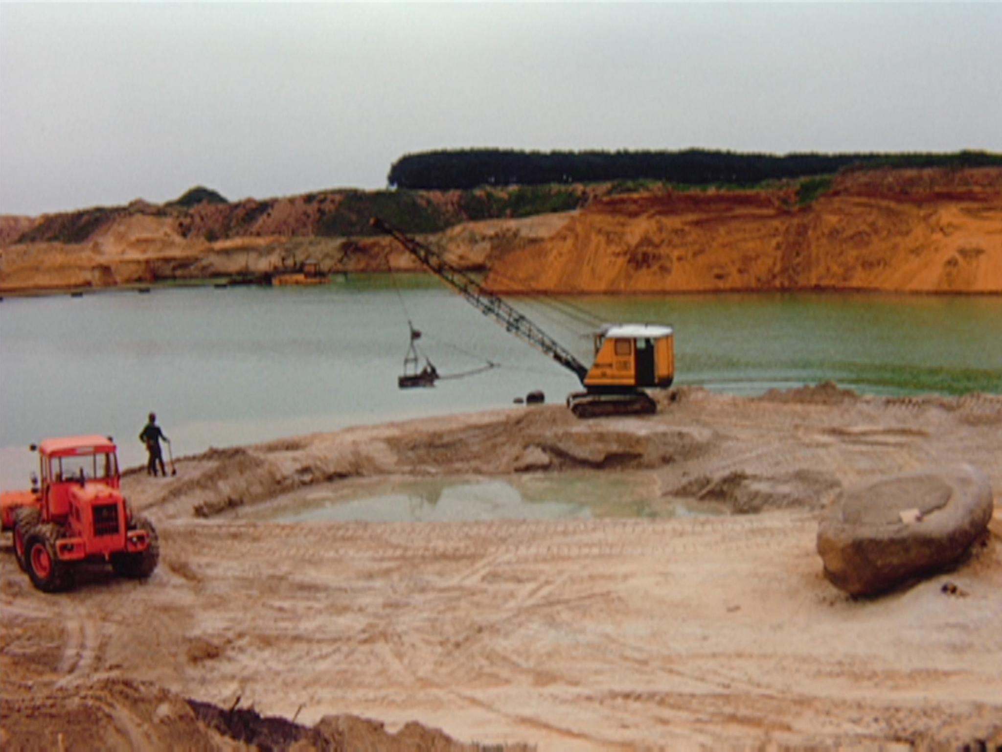 an active sand quarry with a dragline and a lake in the background