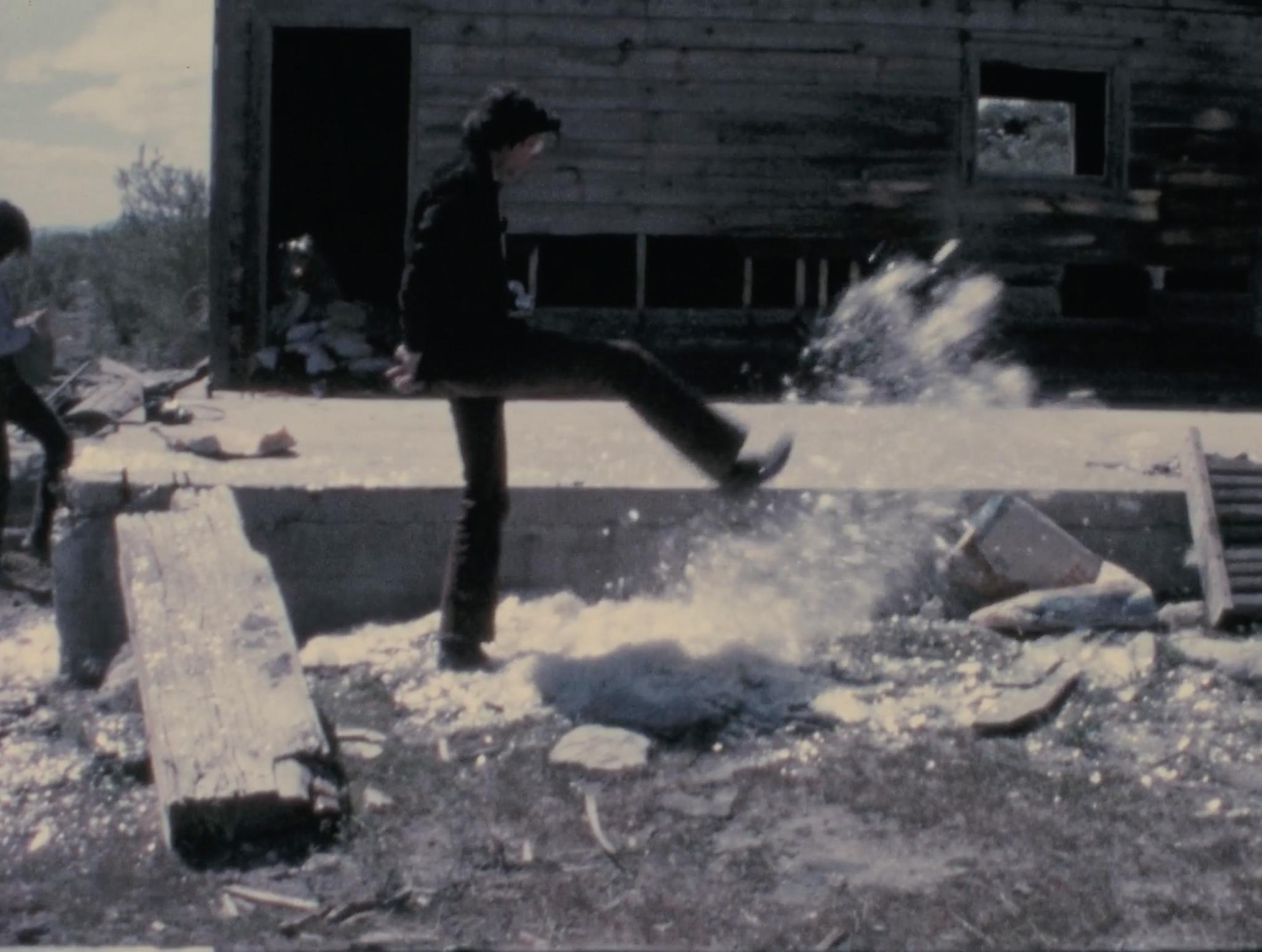 a man kicks a pile of mica and the mica spreads out and flies through the air