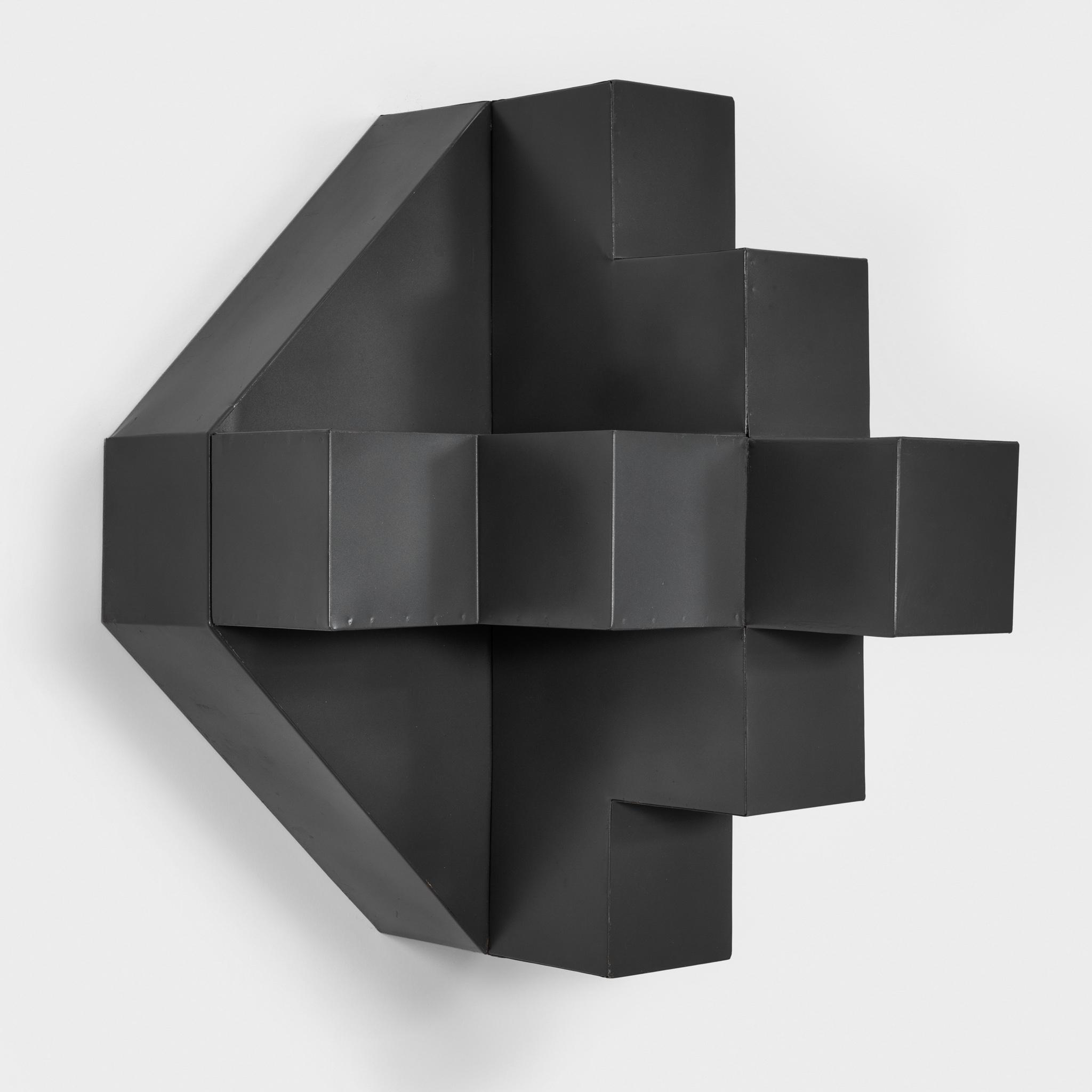 Black painted metal sculpture in a geometric form hanging on the wall 