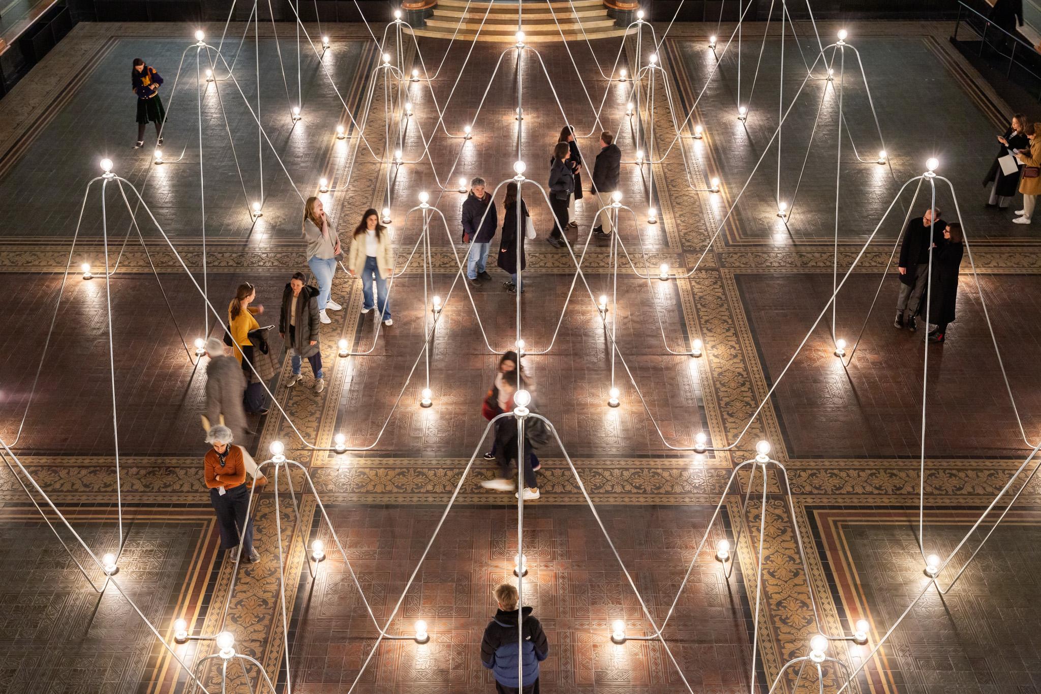 a network of conduit and lightbulbs with people walking throughout