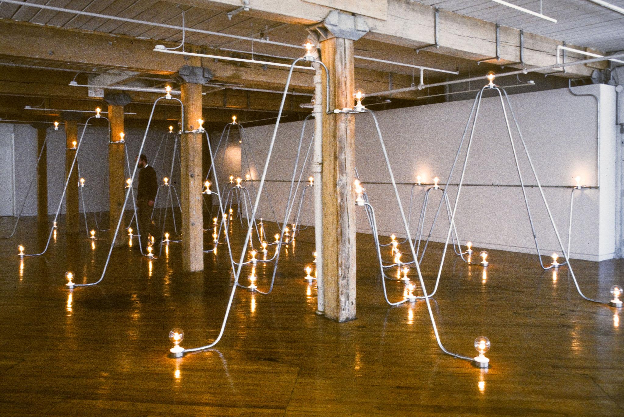 Nancy Holt's Electrical System made of conduit and lightbulbs installed in an exhibition space