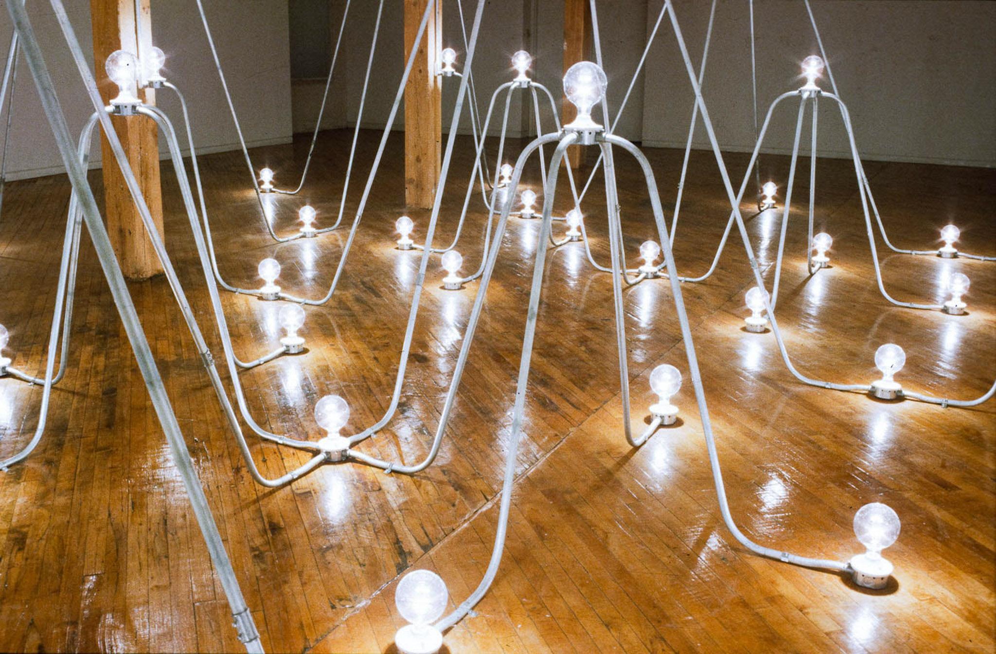 Nancy Holt's Electrical System made of conduit and lightbulbs installed in an exhibition space