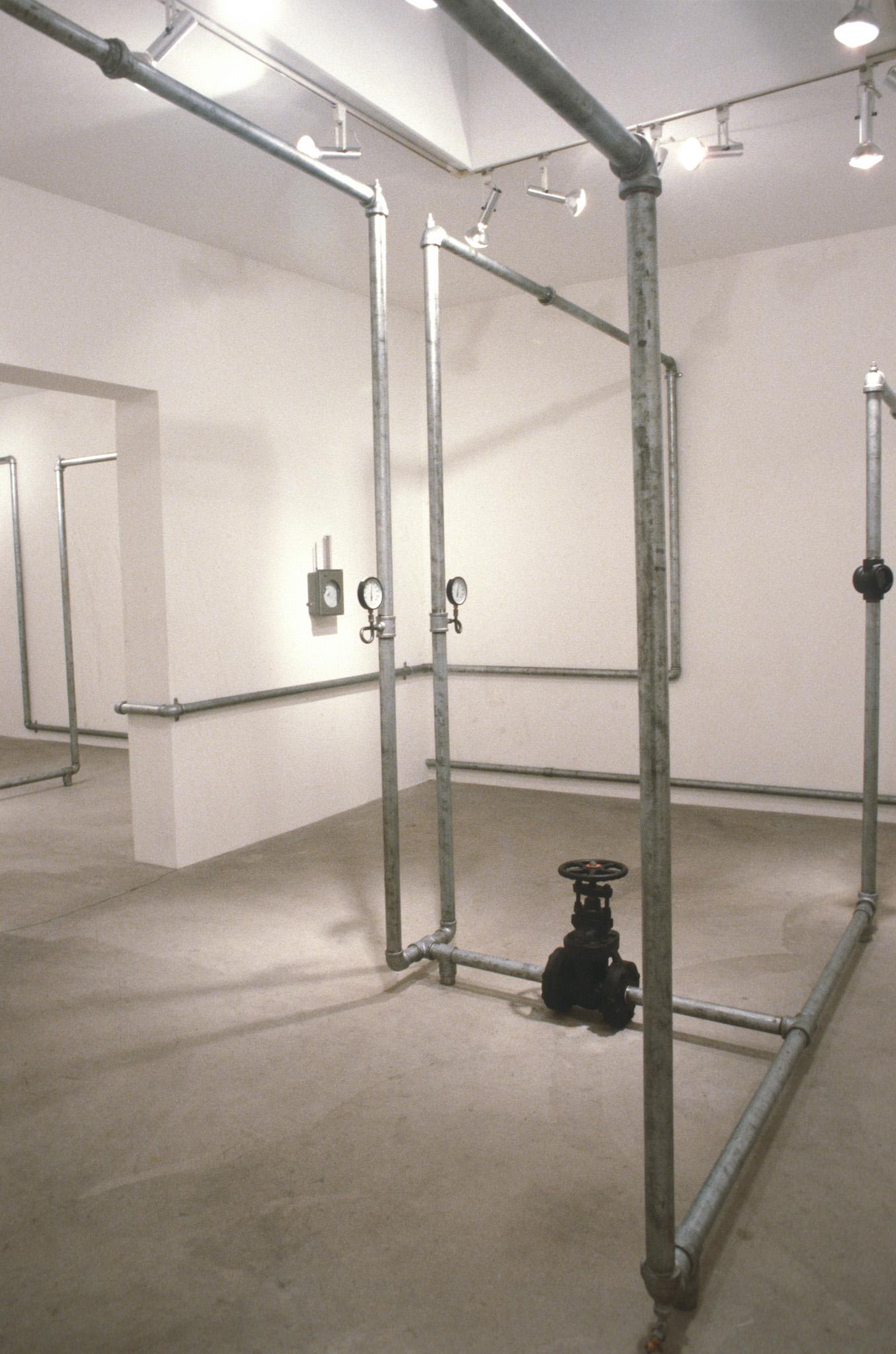 An installation of hot water pipes and gauges installed in a white walled gallery space
