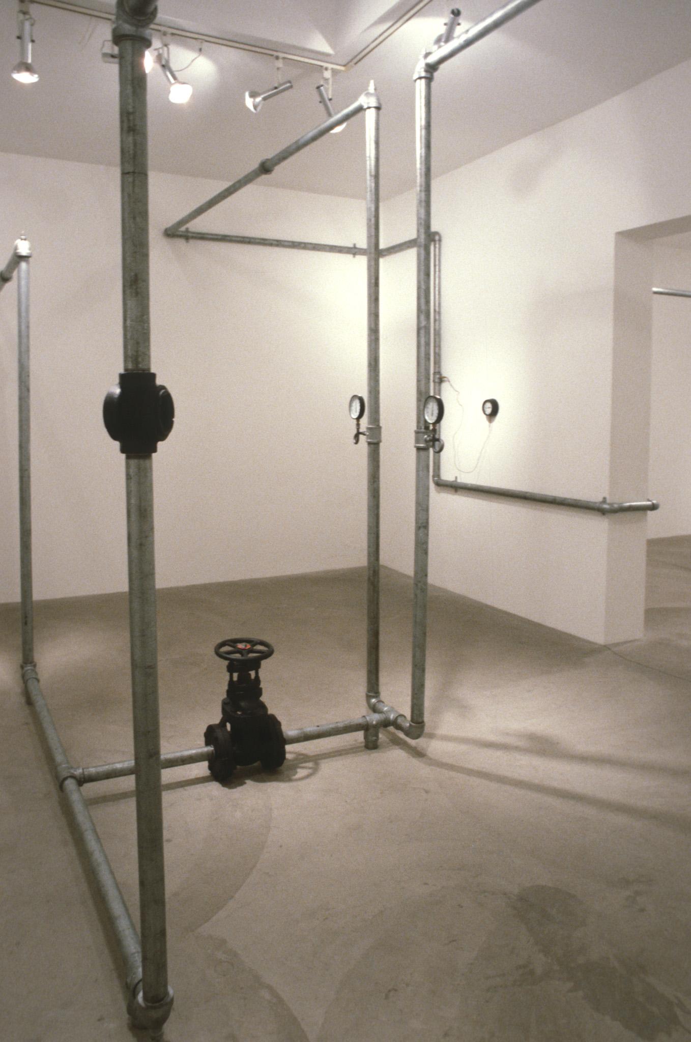 An installation of hot water pipes and gauges installed in a white walled gallery space