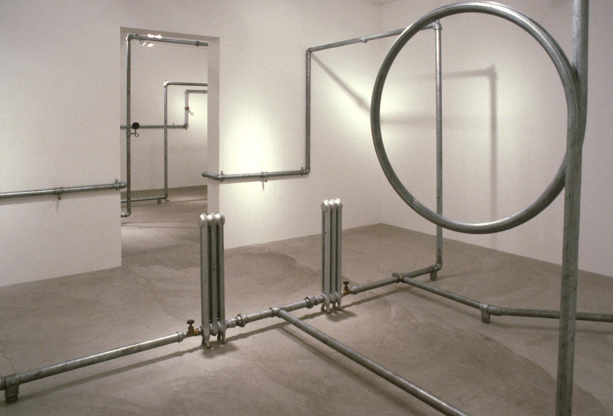An installation of hot water pipes and gauges installed in a white walled gallery space