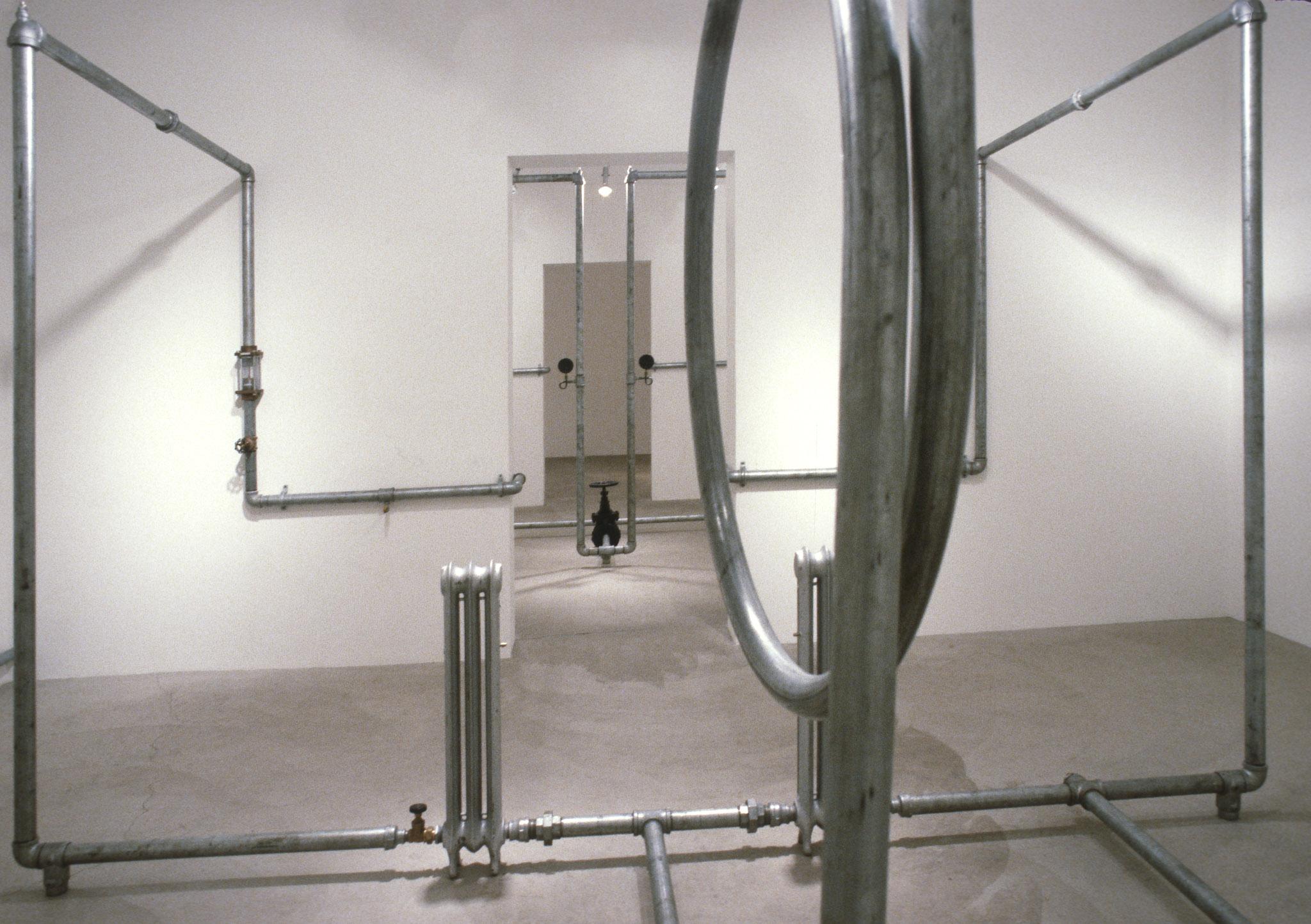 An installation of hot water pipes and gauges installed in a white walled gallery space