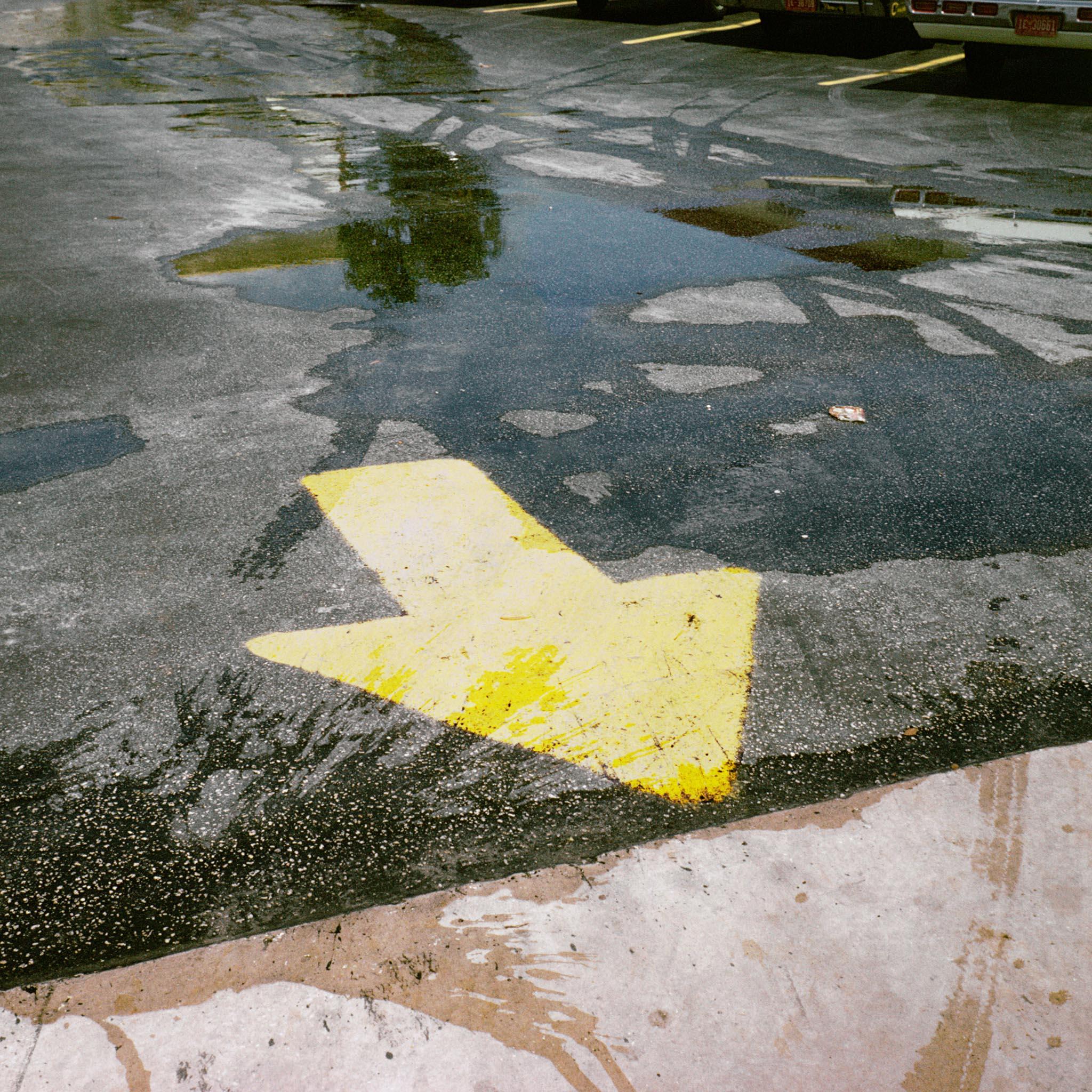 a wet parking lot with a large yellow arrow