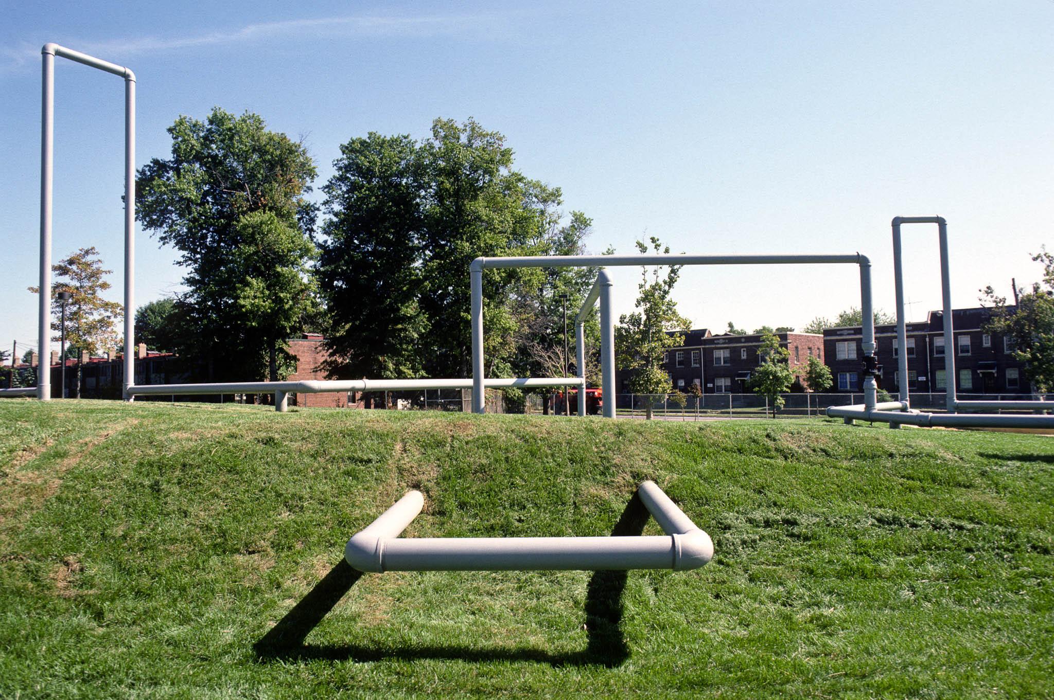 a sculpture made of large metal piping on a slope