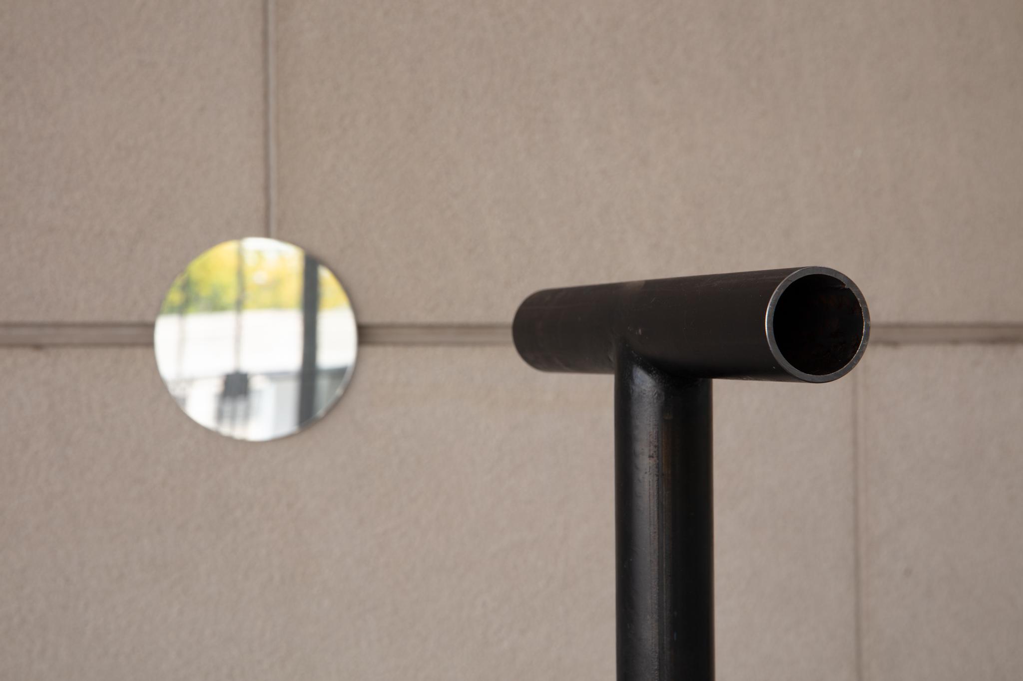 a freestanding metal pipe and a circular mirror mounted on a wall
