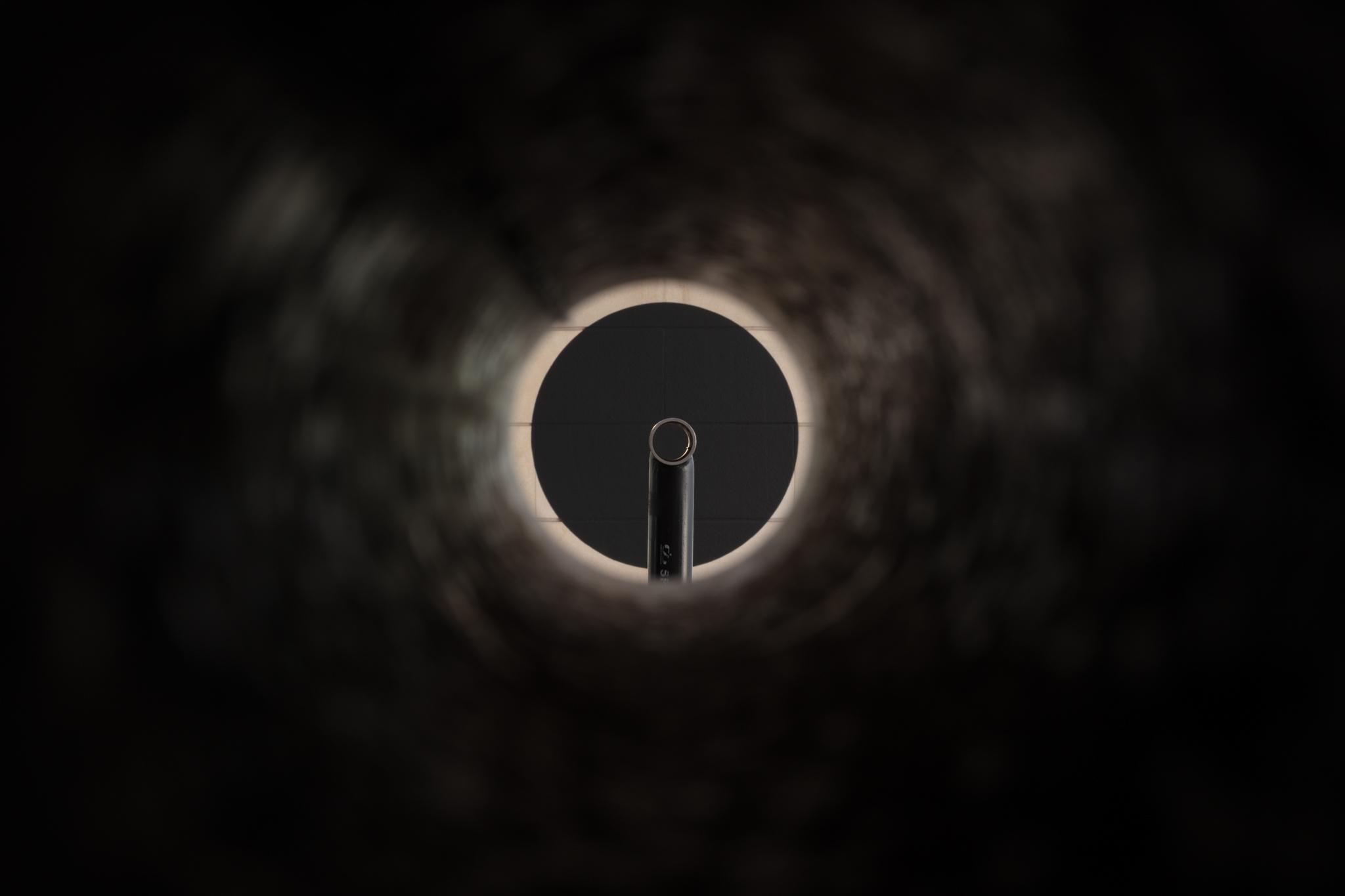 An interior view of a pipe looking at another pipe and large painted black circle