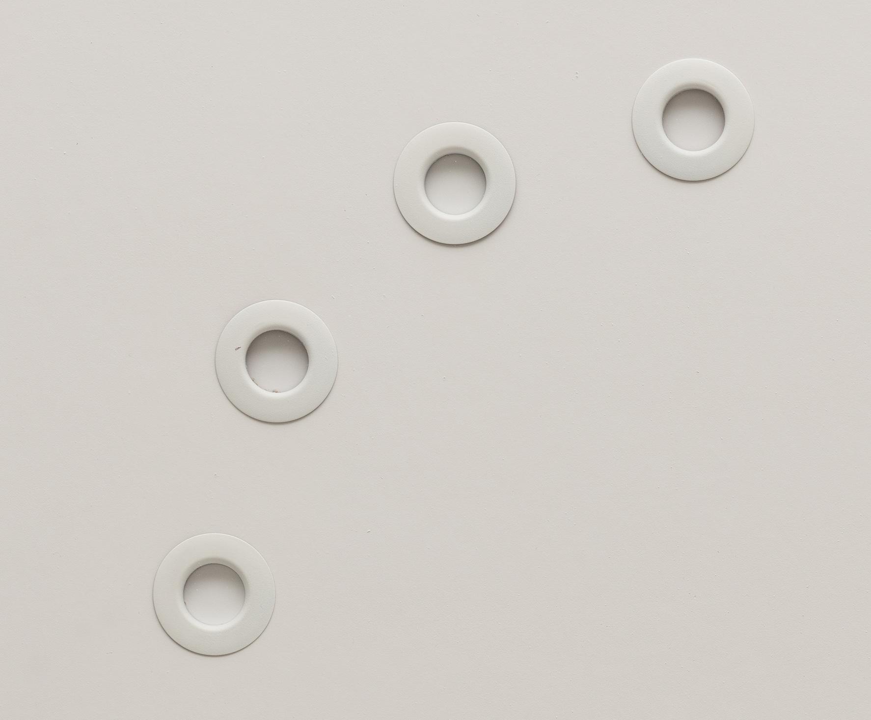 Circular white grommets arranged in a circle on white foamcore