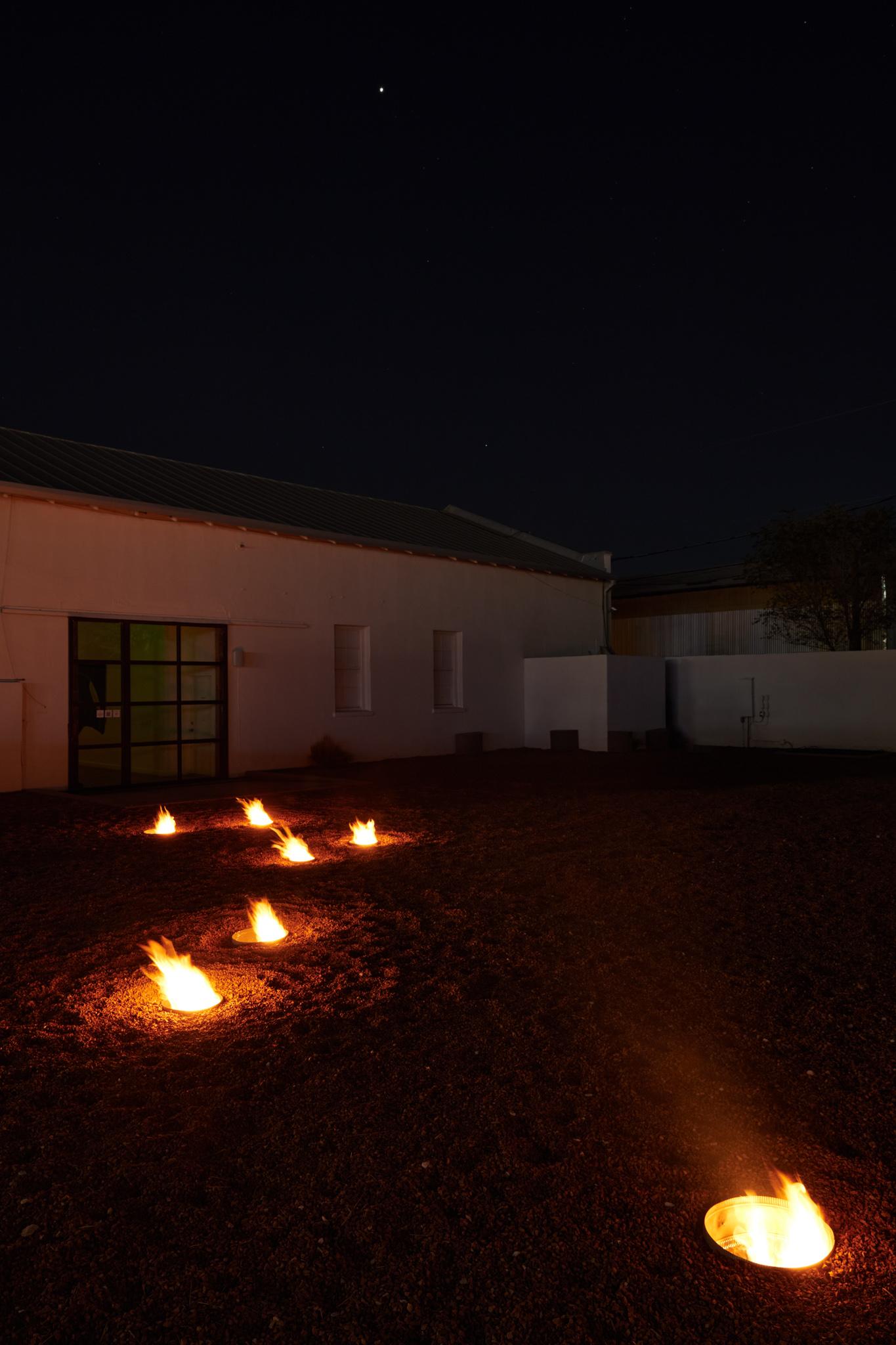 a courtyard with several small firepits in the ground spaced out in the shape of the big dipper