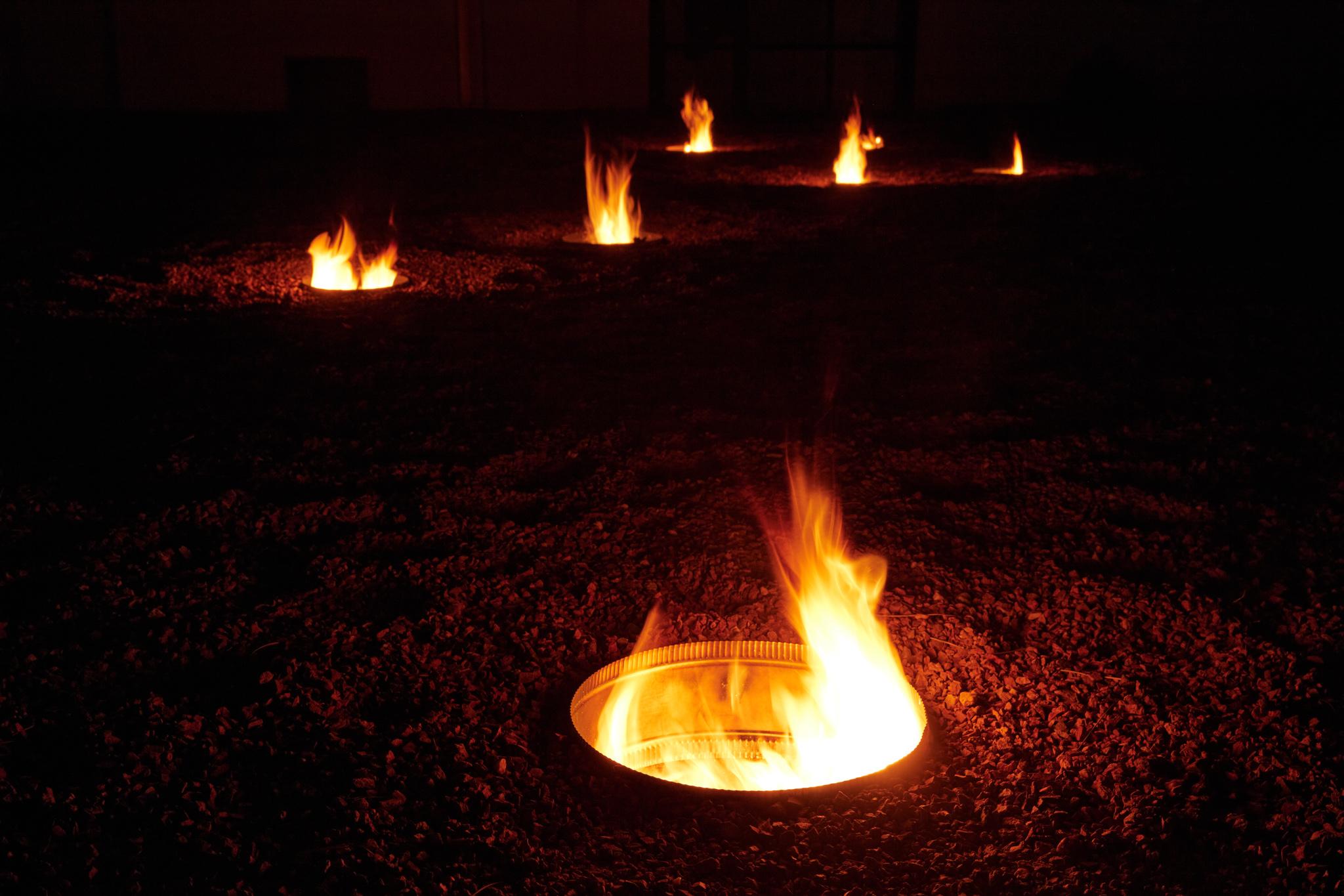 a courtyard with several small firepits in the ground spaced out in the shape of the big dipper