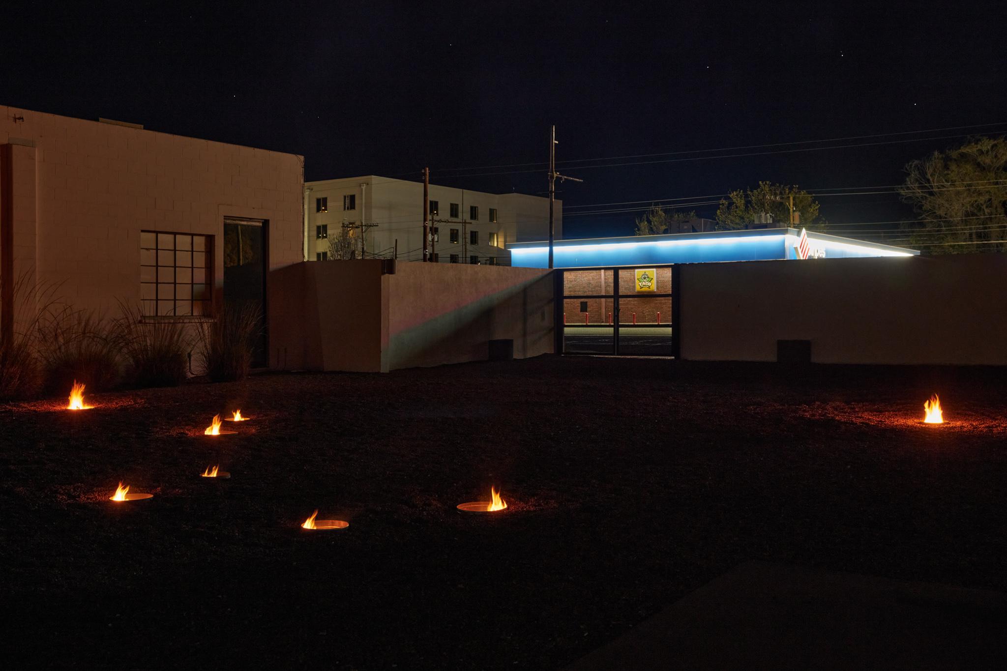 a courtyard with several small firepits in the ground spaced out in the shape of the big dipper