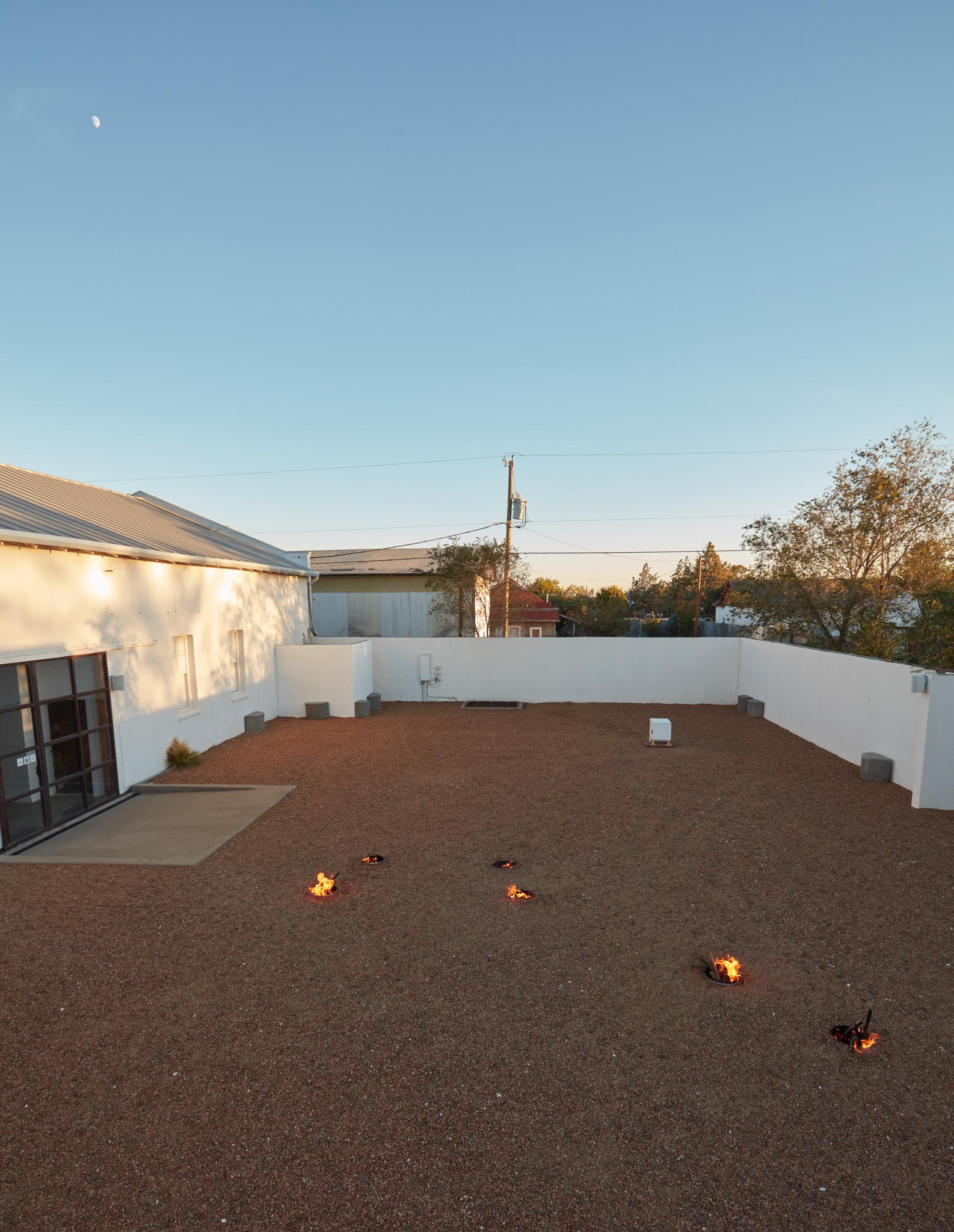 a courtyard with gravel and small firepits arranged in in the shape of the big dipper