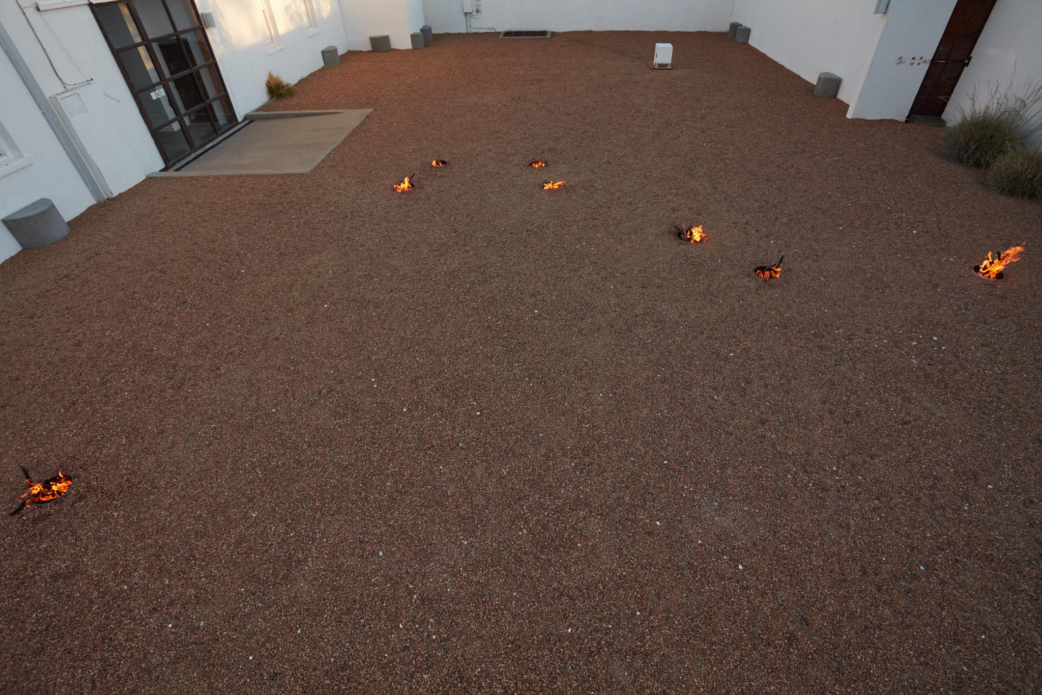 a courtyard with gravel and small firepits arranged in in the shape of the big dipper