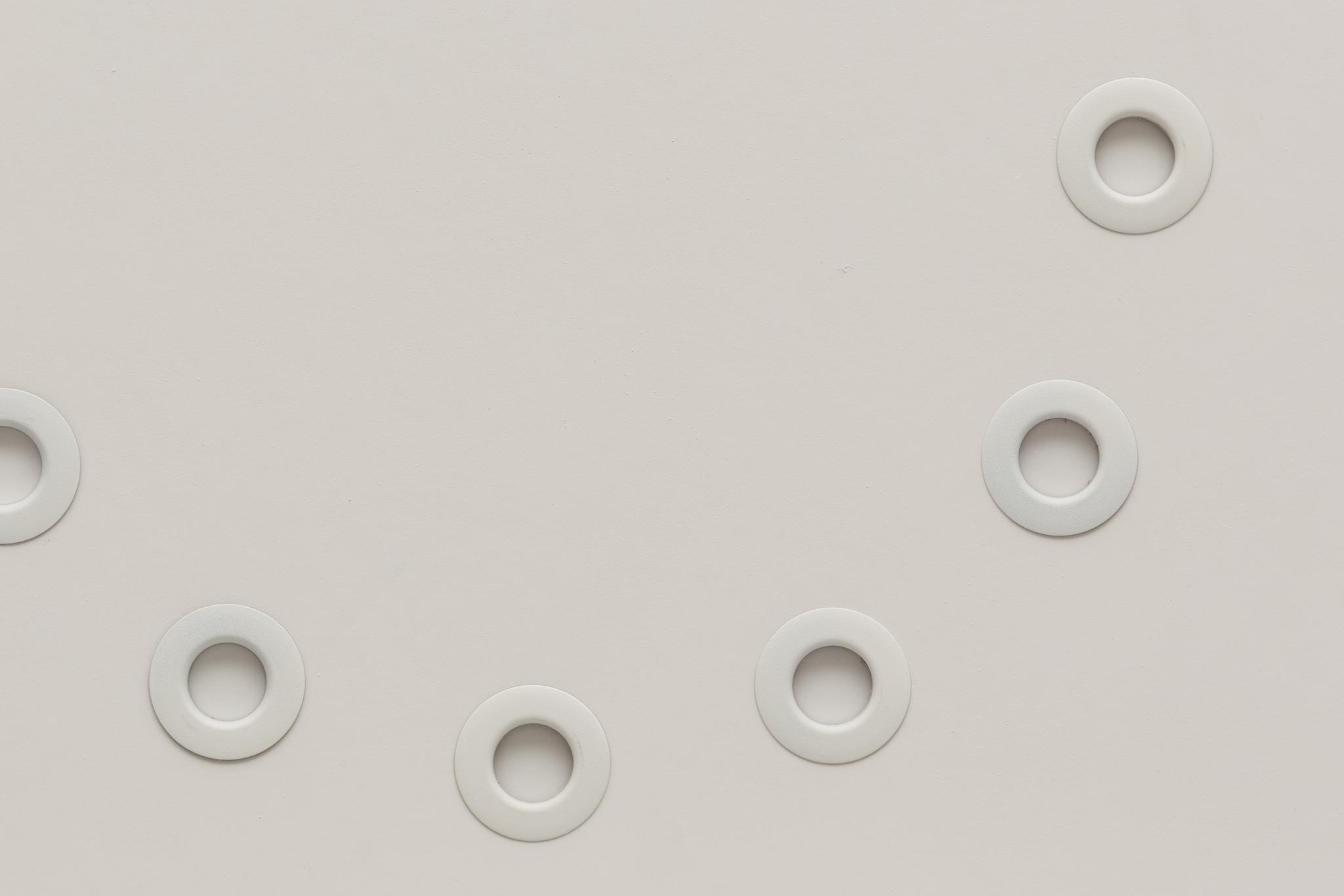 Circular white grommets arranged in a circle on white foamcore