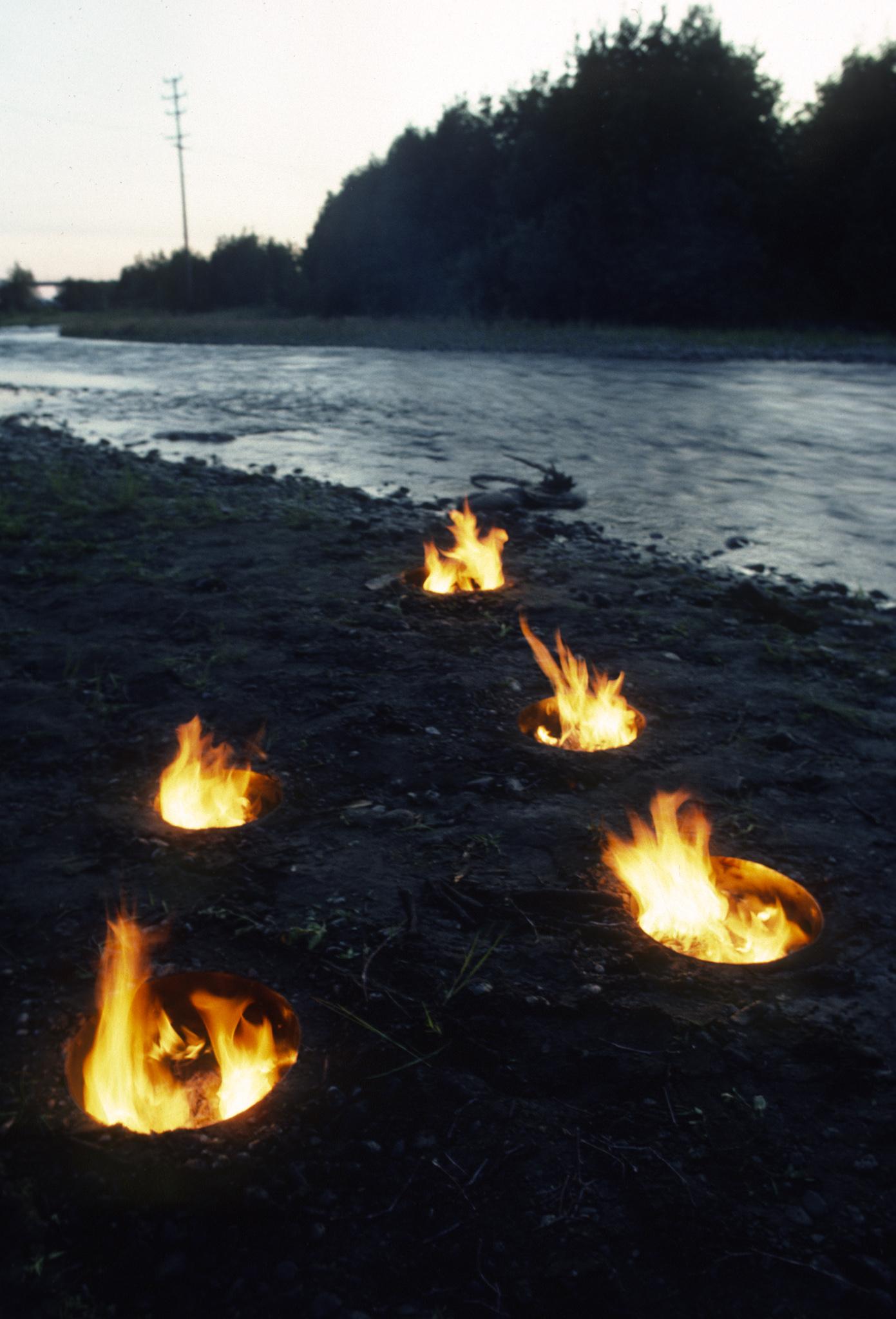 a small island in a river that has firepits arranged in the shape of the big dipper