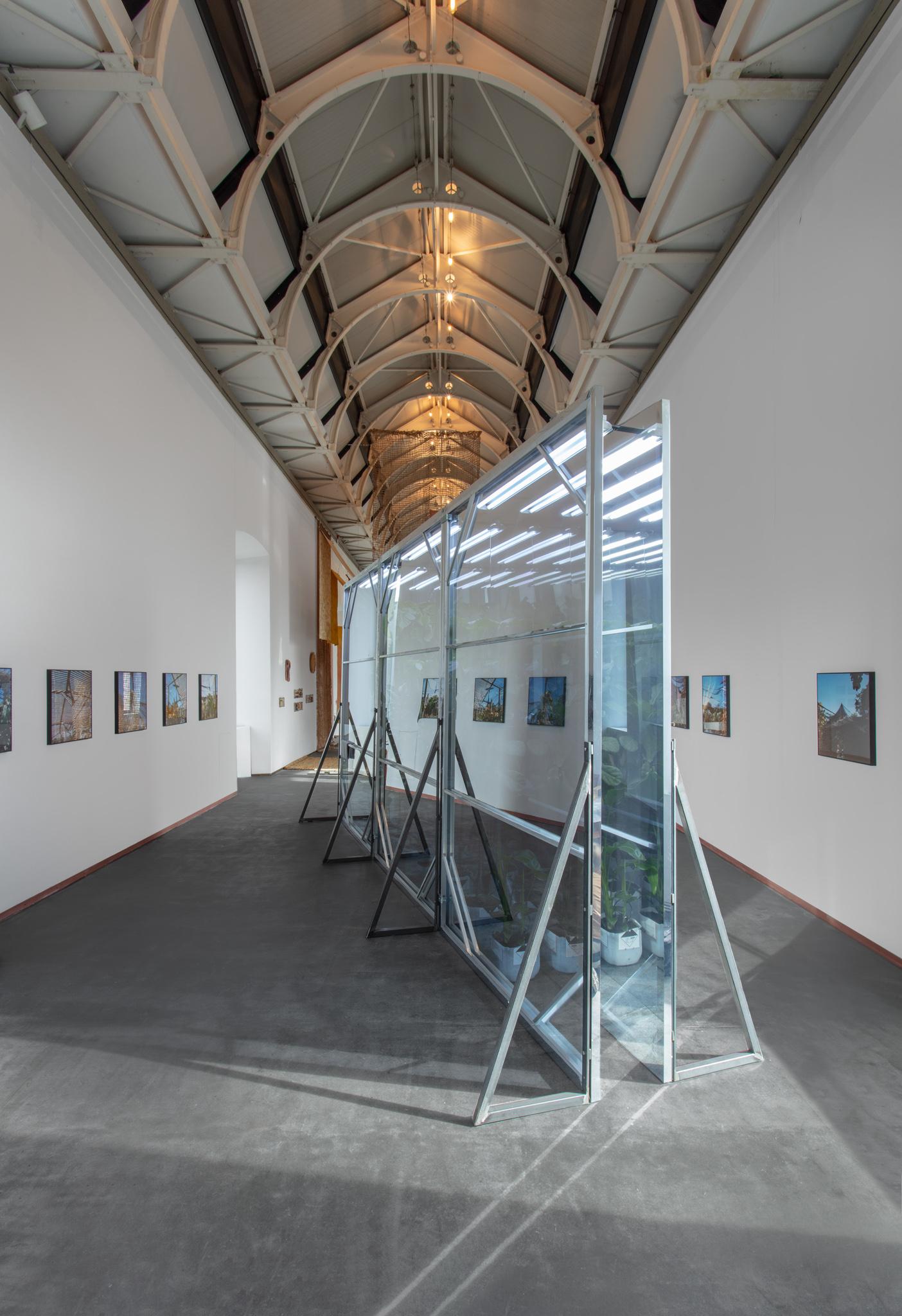 a tall gallery space with artworks on the walls and a large sculpture in the center
