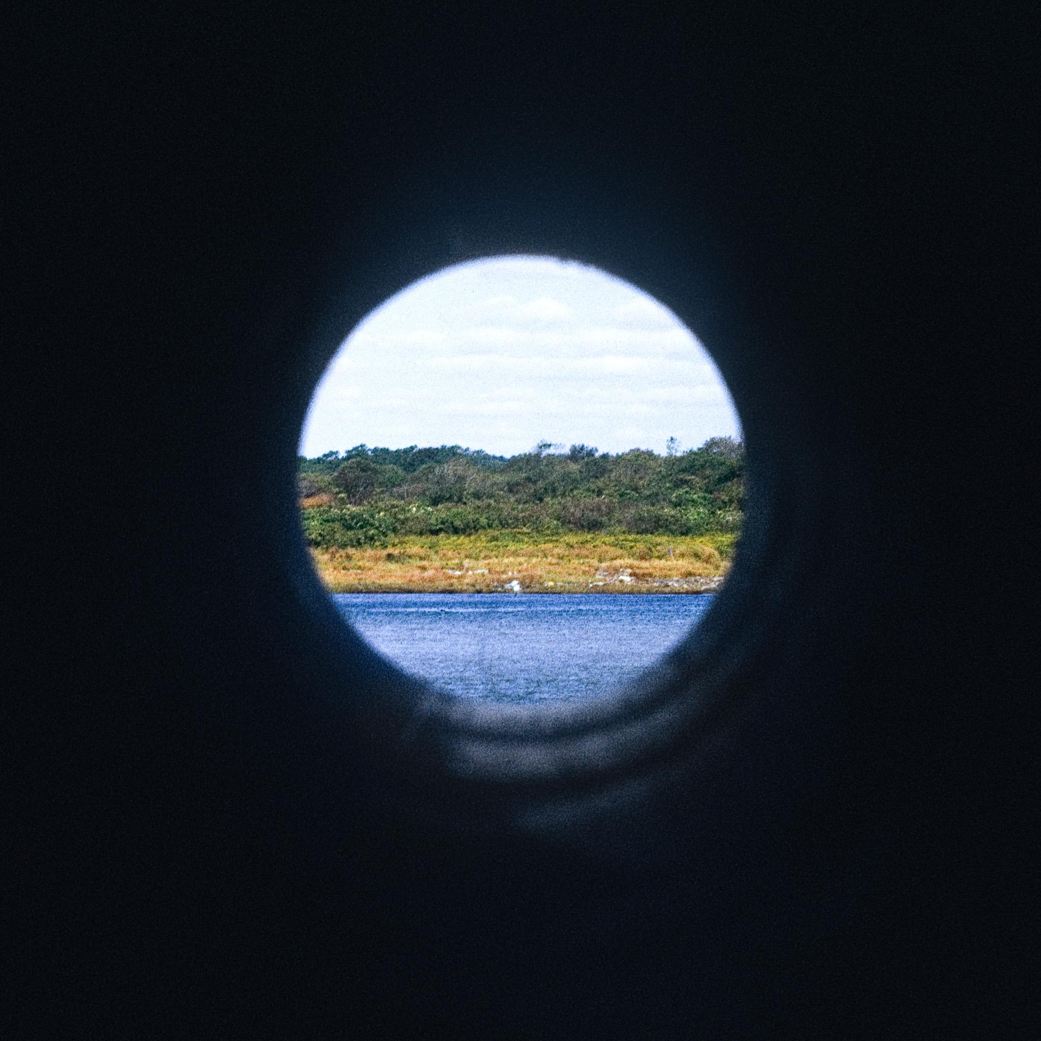 A circular pipe framing a view of ocean and landscape horizons