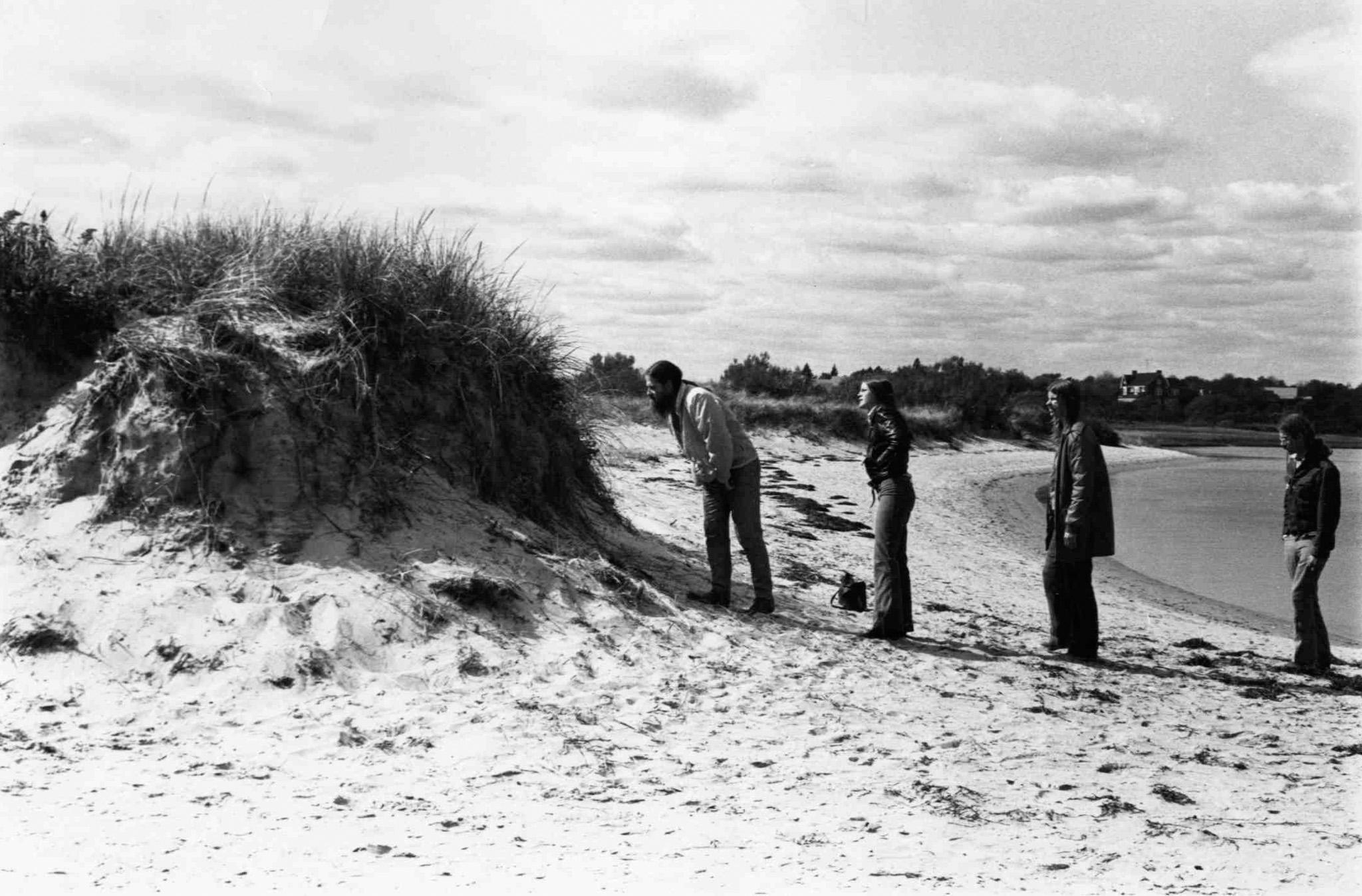 Student's lined up to look through Nancy Holt's Views Through a Sand Dune (1972) on a beach