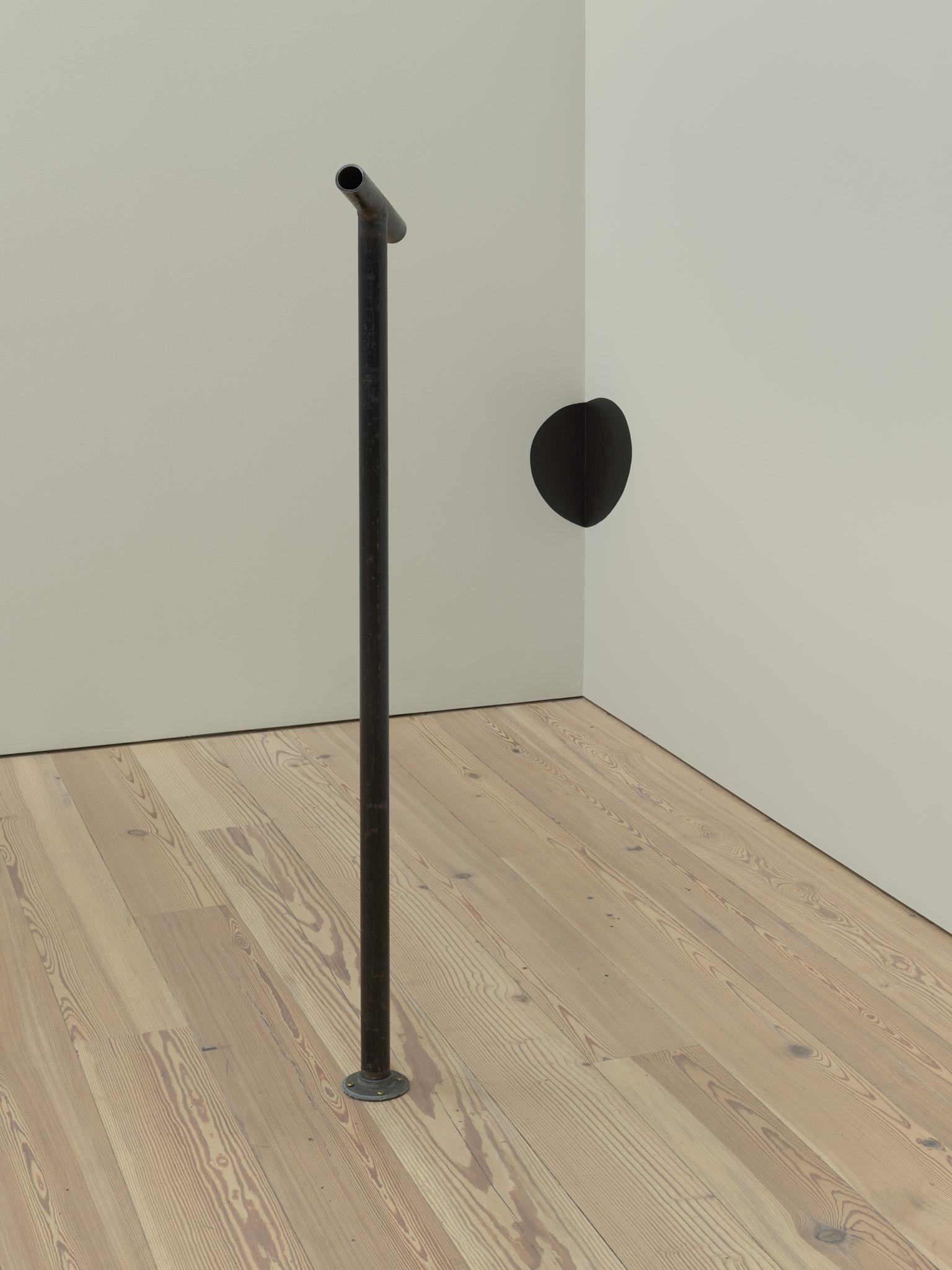 Nancy Holt's Locator (Studio Corner) on view at the Whitney Museum. A black metal pipe looking at a black circle painted on the wall