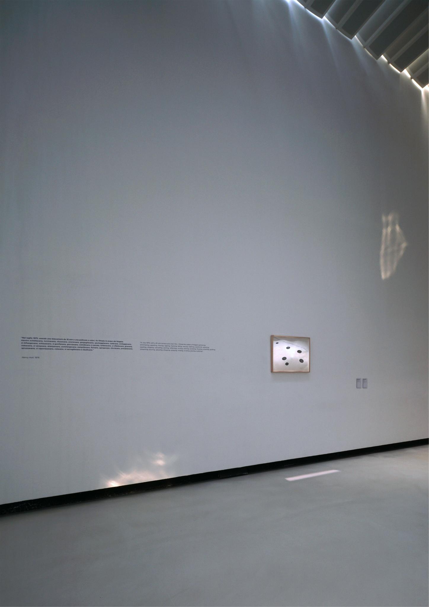 installation view of a tall museum gallery space with a drawing on one wall