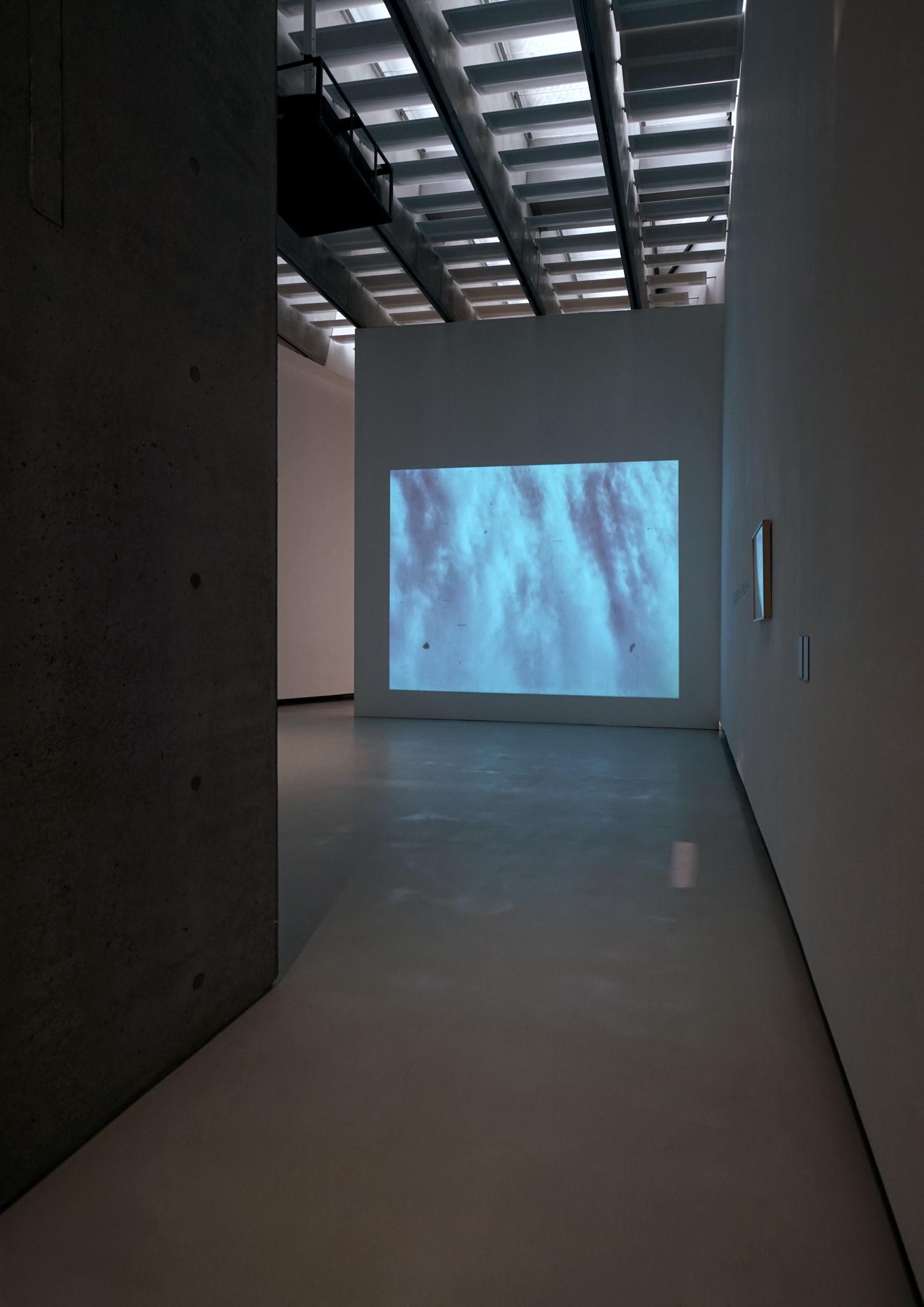 installation view of a tall museum gallery space with a projection of water on one wall