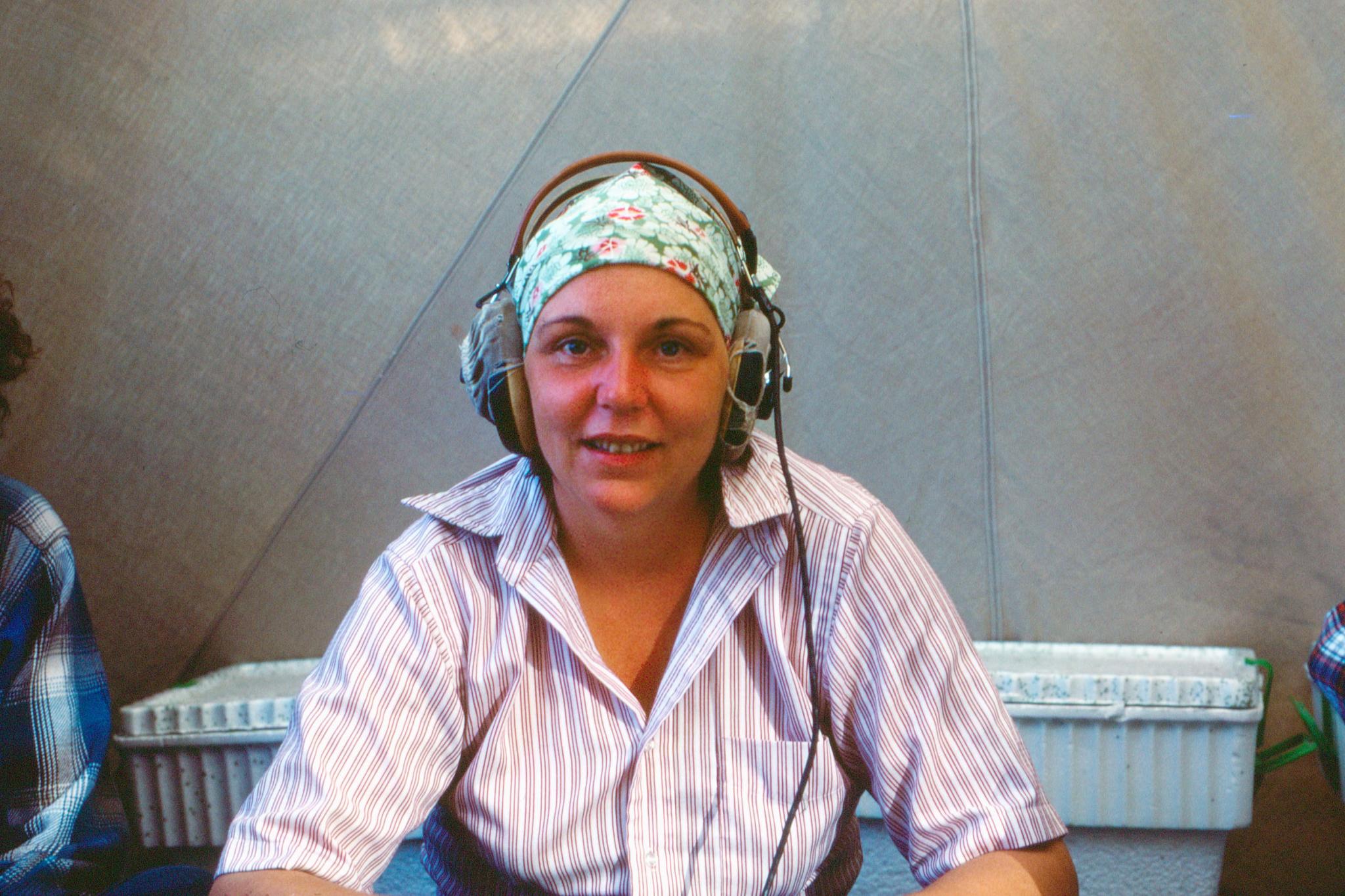 a woman wearing headphones and a head scarf inside a tent