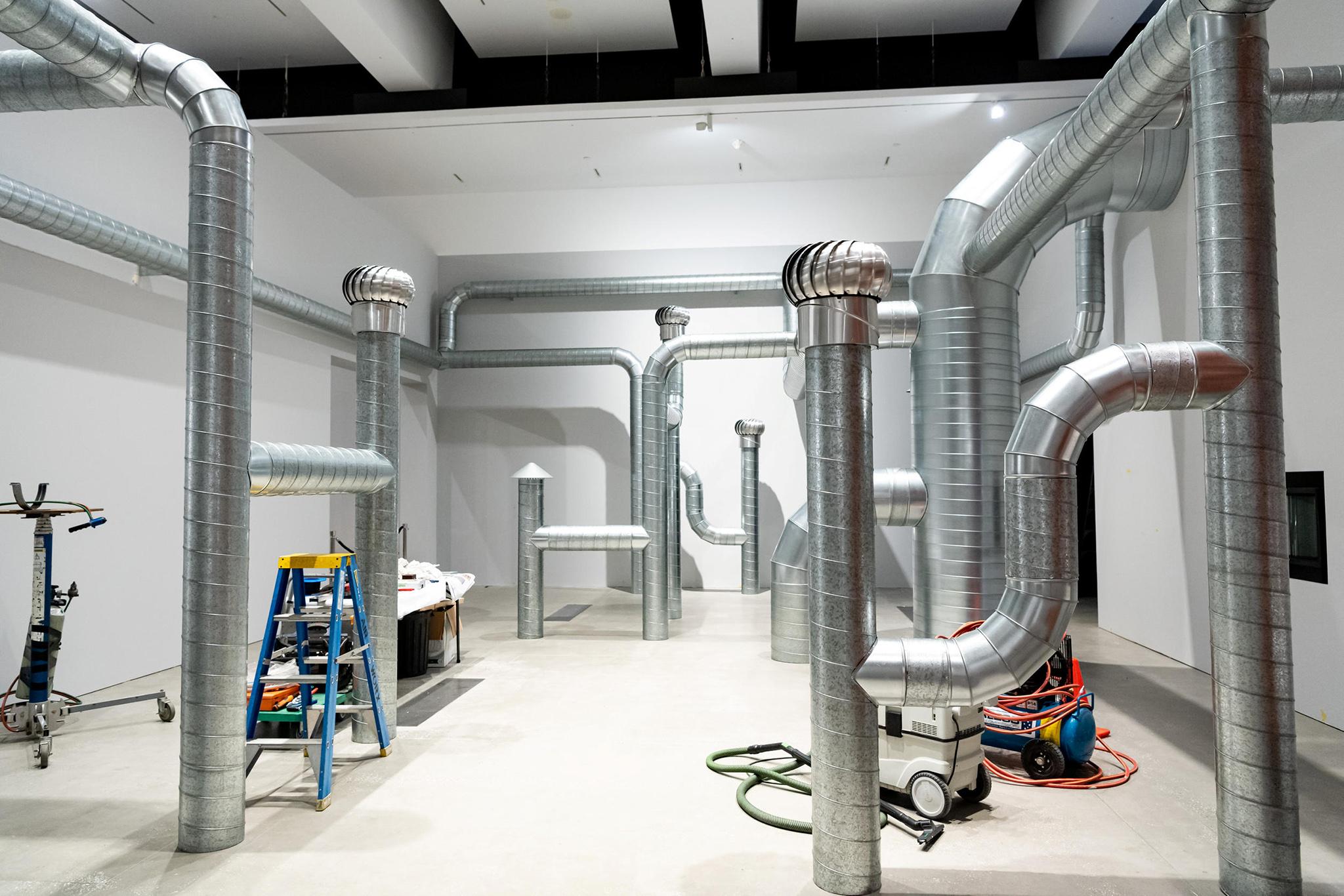 a network of steel ventilation ducting installed in a white walled room