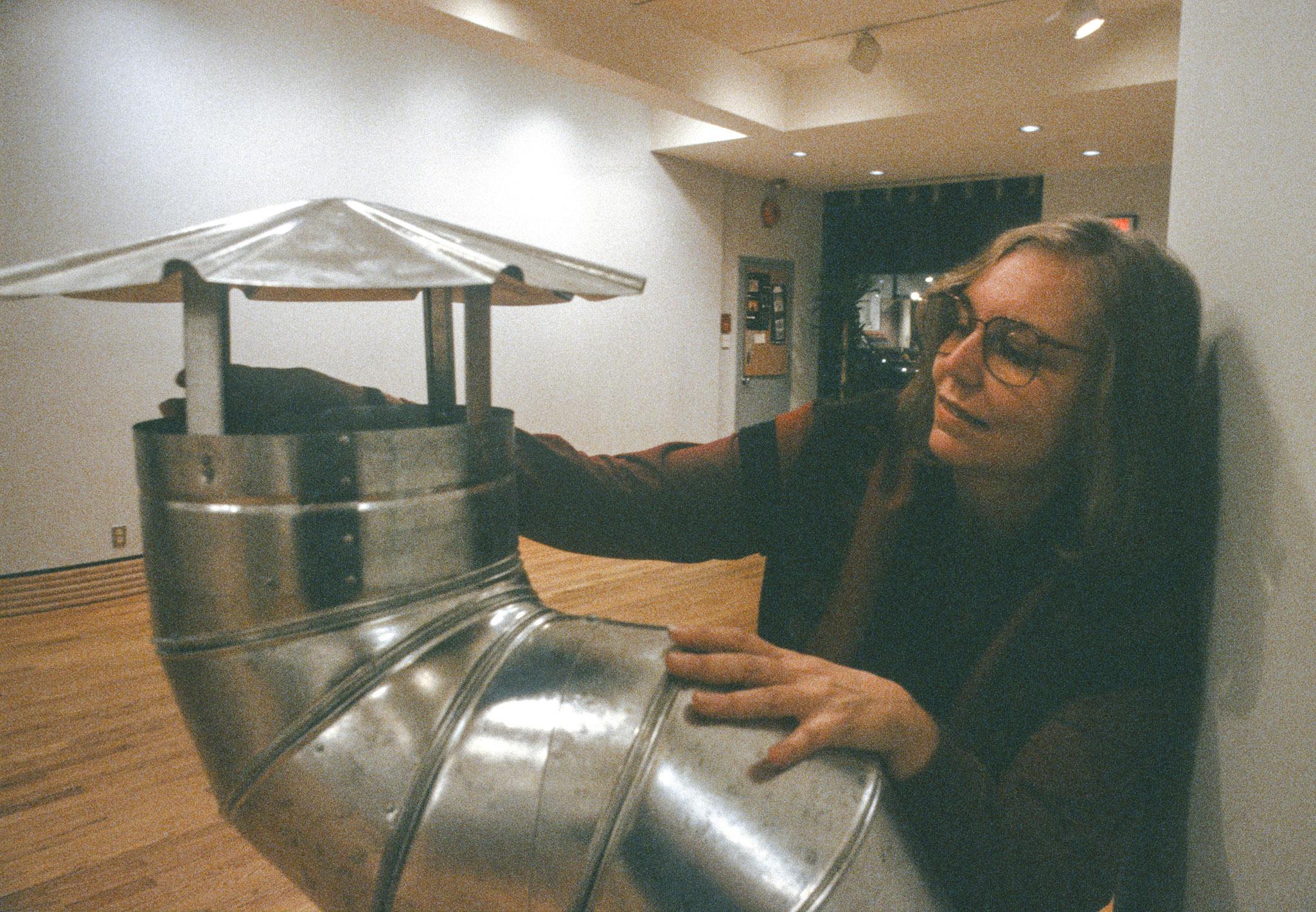 a woman leaning looking at a ventilation pipe and shanty cap
