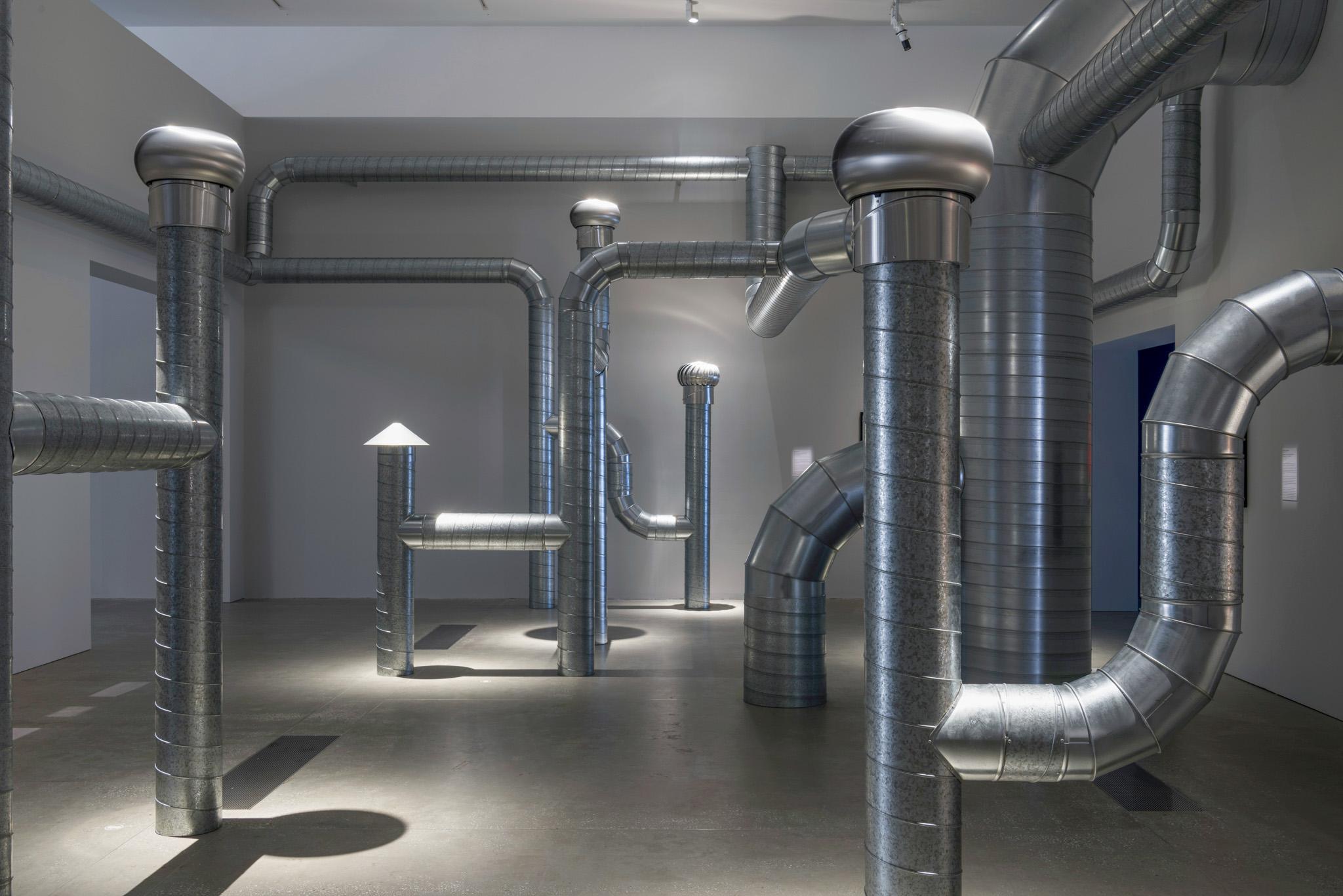 a network of steel ventilation ducting installed in a white walled room