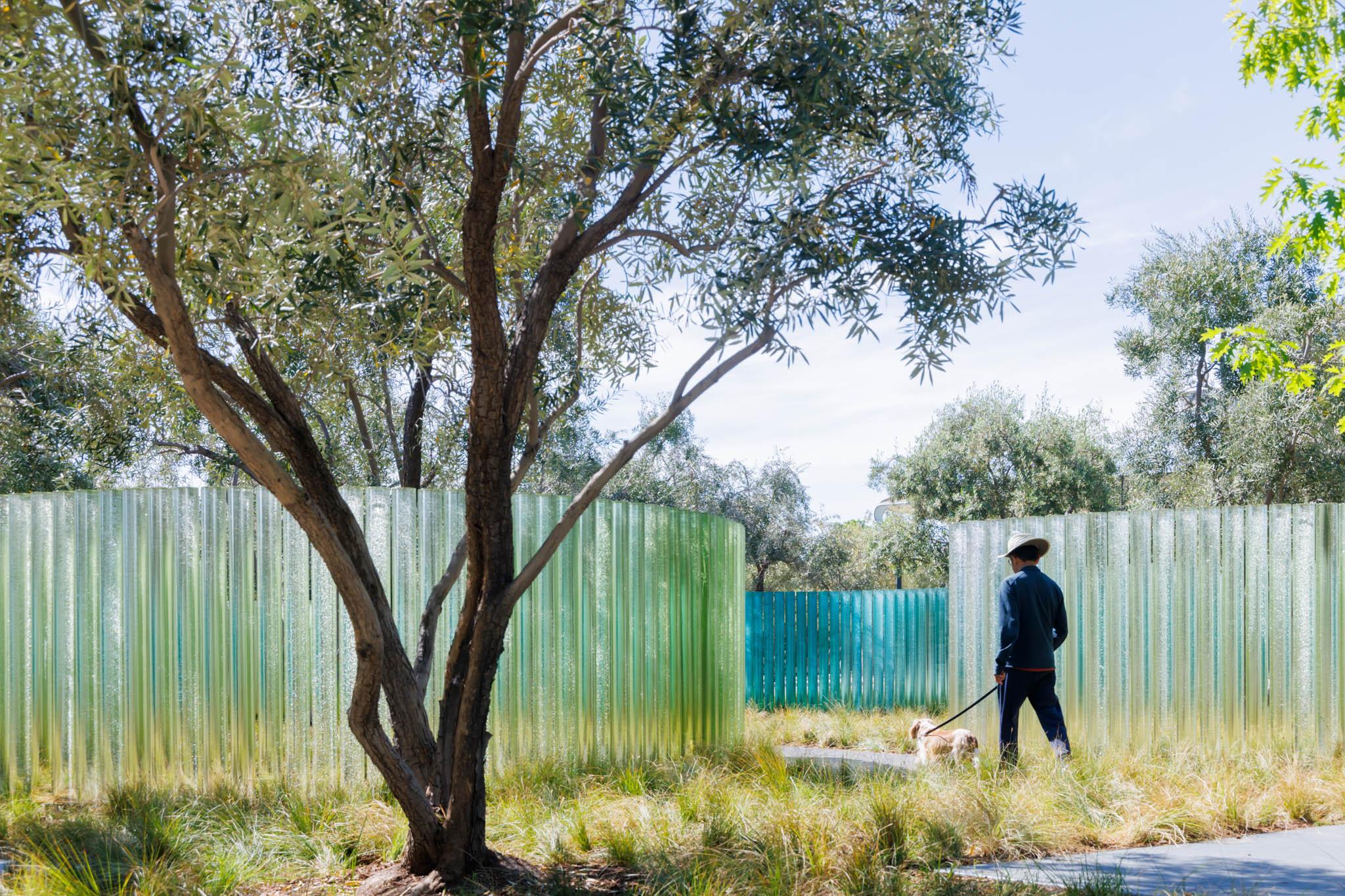 a park with a large glass sculptural wall within it