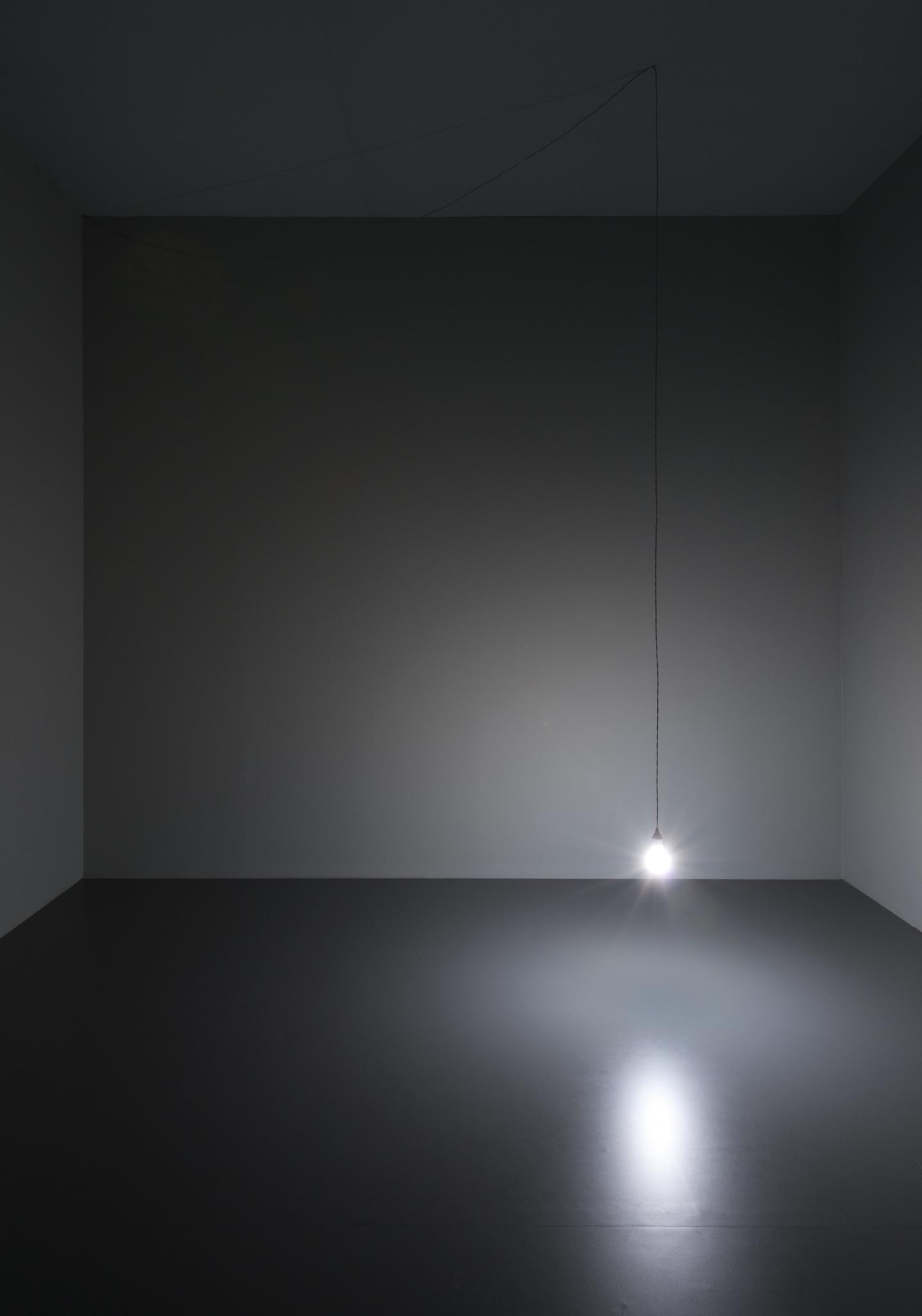 a dark room with a single lightbulb hanging low from the ceiling