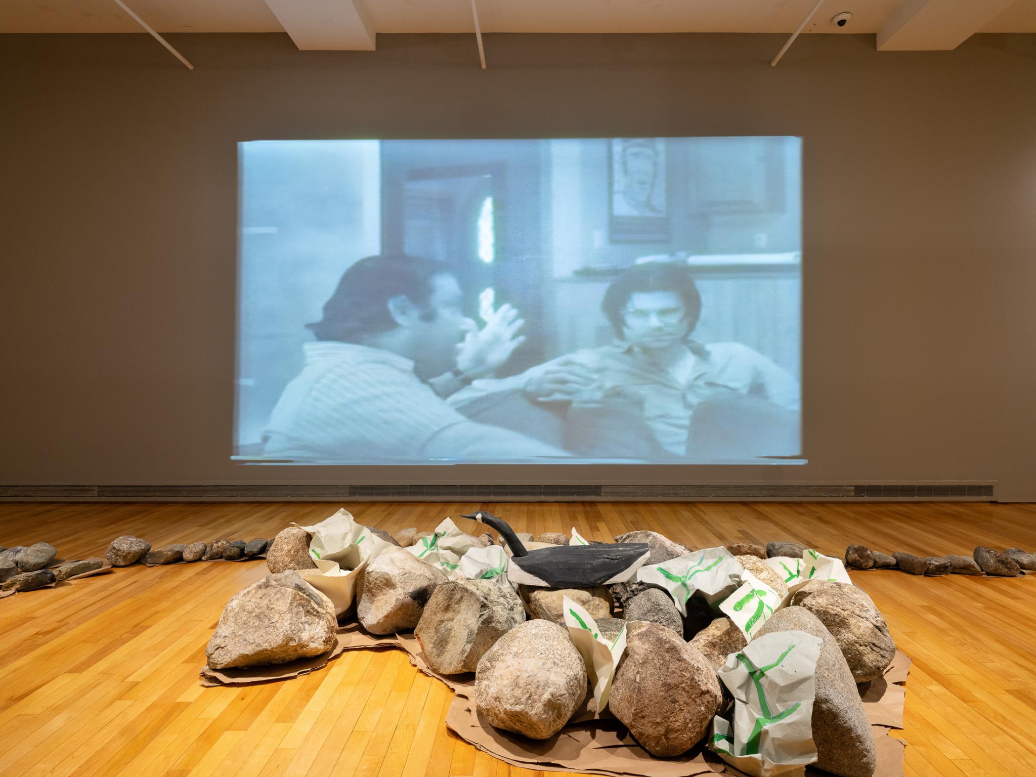 a group of rocks and a video projection showing two men talking