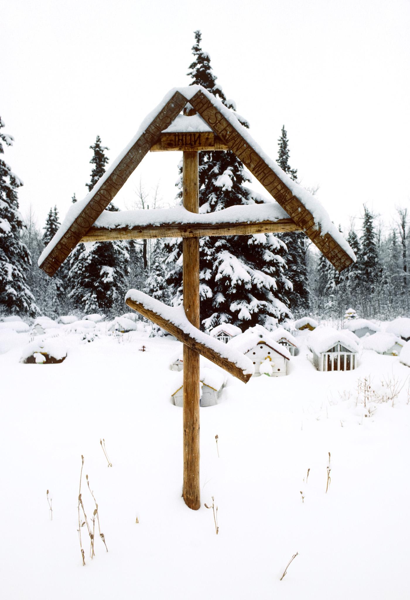 a Russian orthodox crucifix outisde in the snow at a graveyard