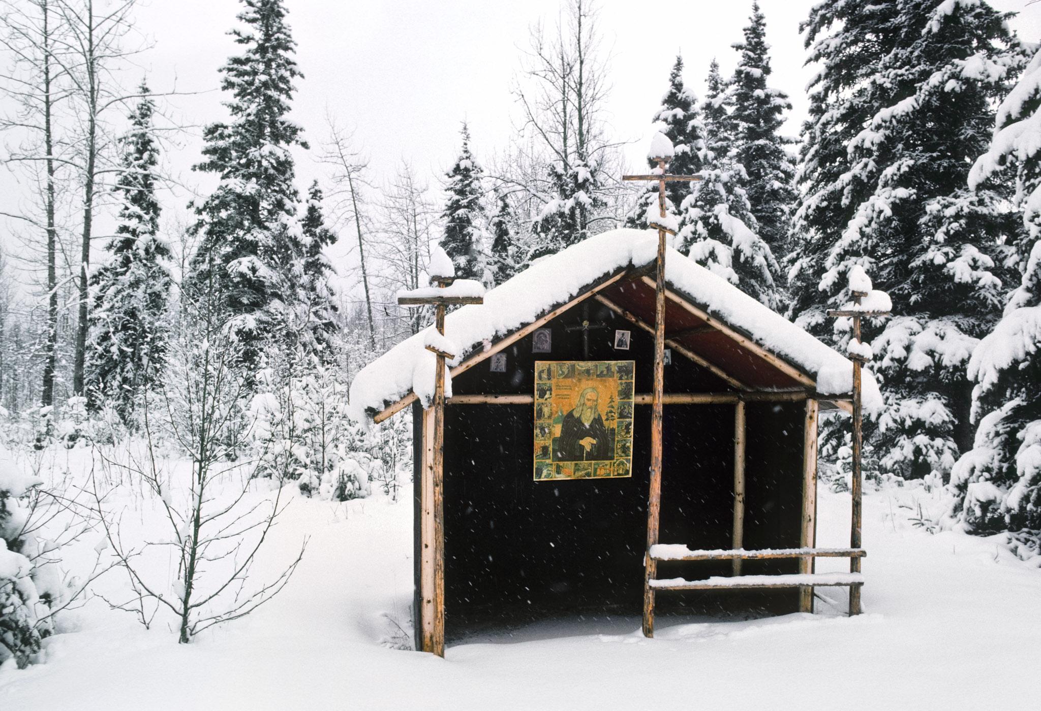 a snowy graveyard with large house-like structures as gravemarkers