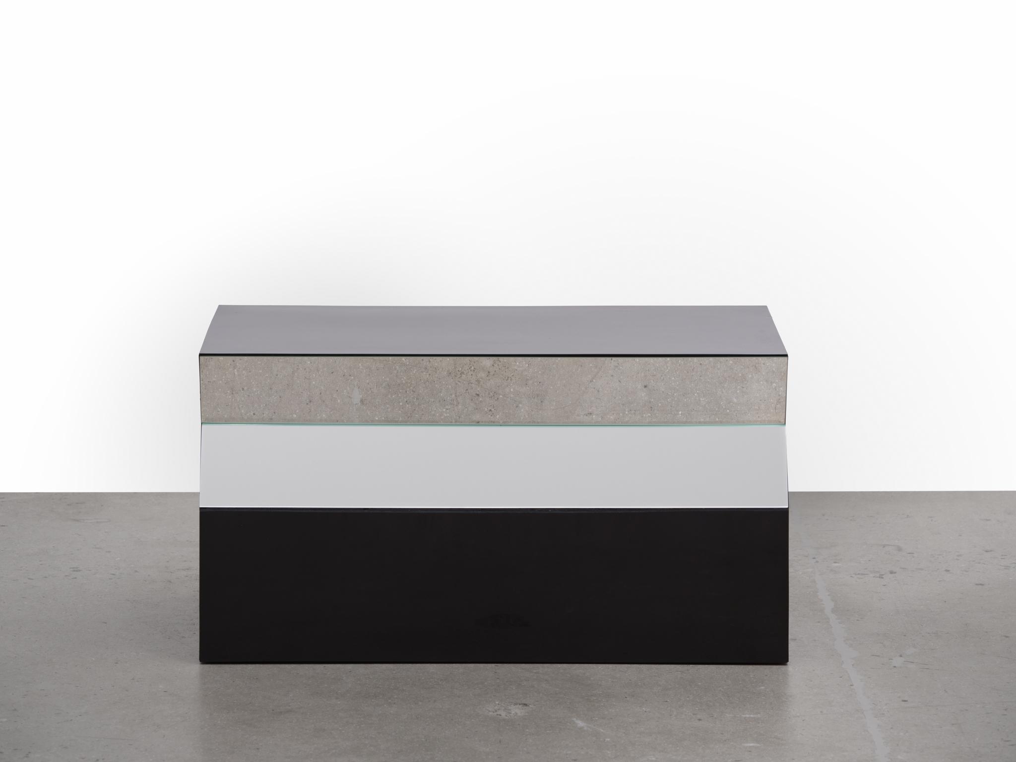 a geometric sculpture made of formica and mirrors sitting on a concrete floor