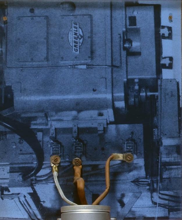 section of a wall based sculpture with collage and a machine