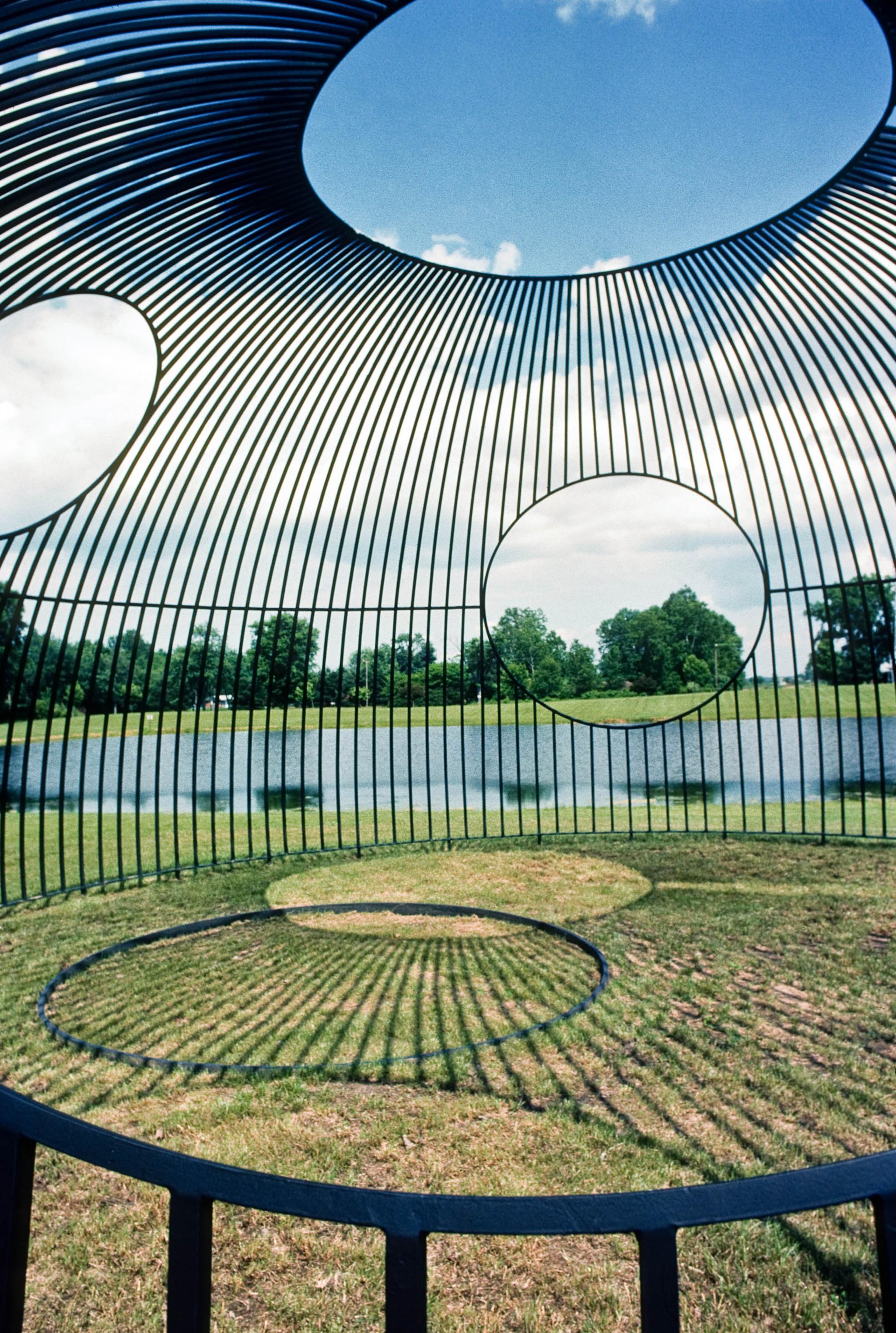an outdoor sculpture made of steel bars in a hemisphere