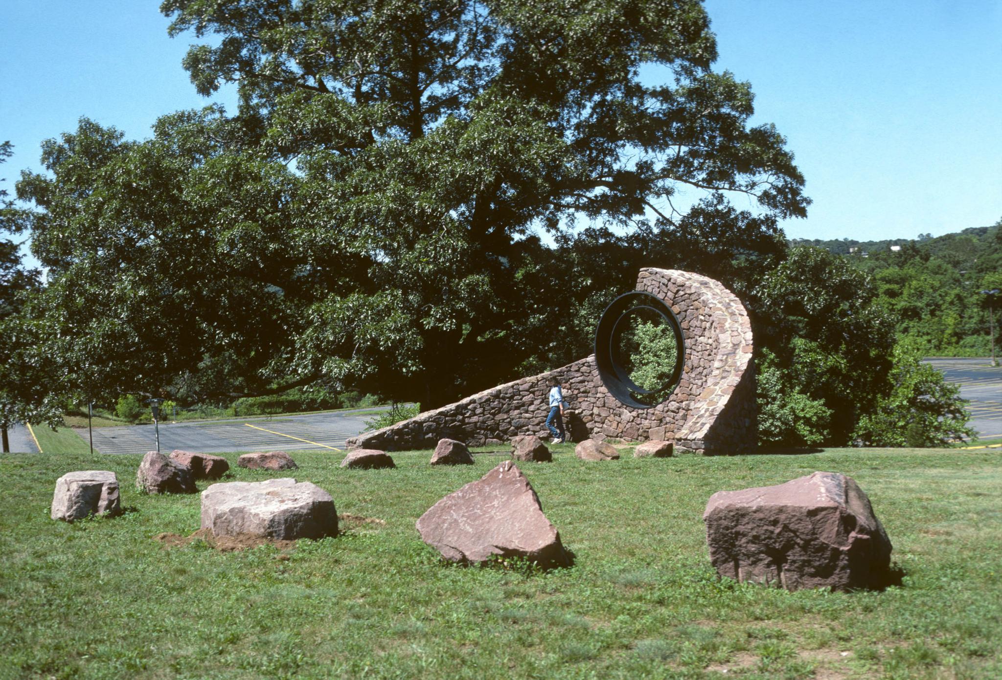 a sculpture made of a curved stone wall with a viewing circle within it