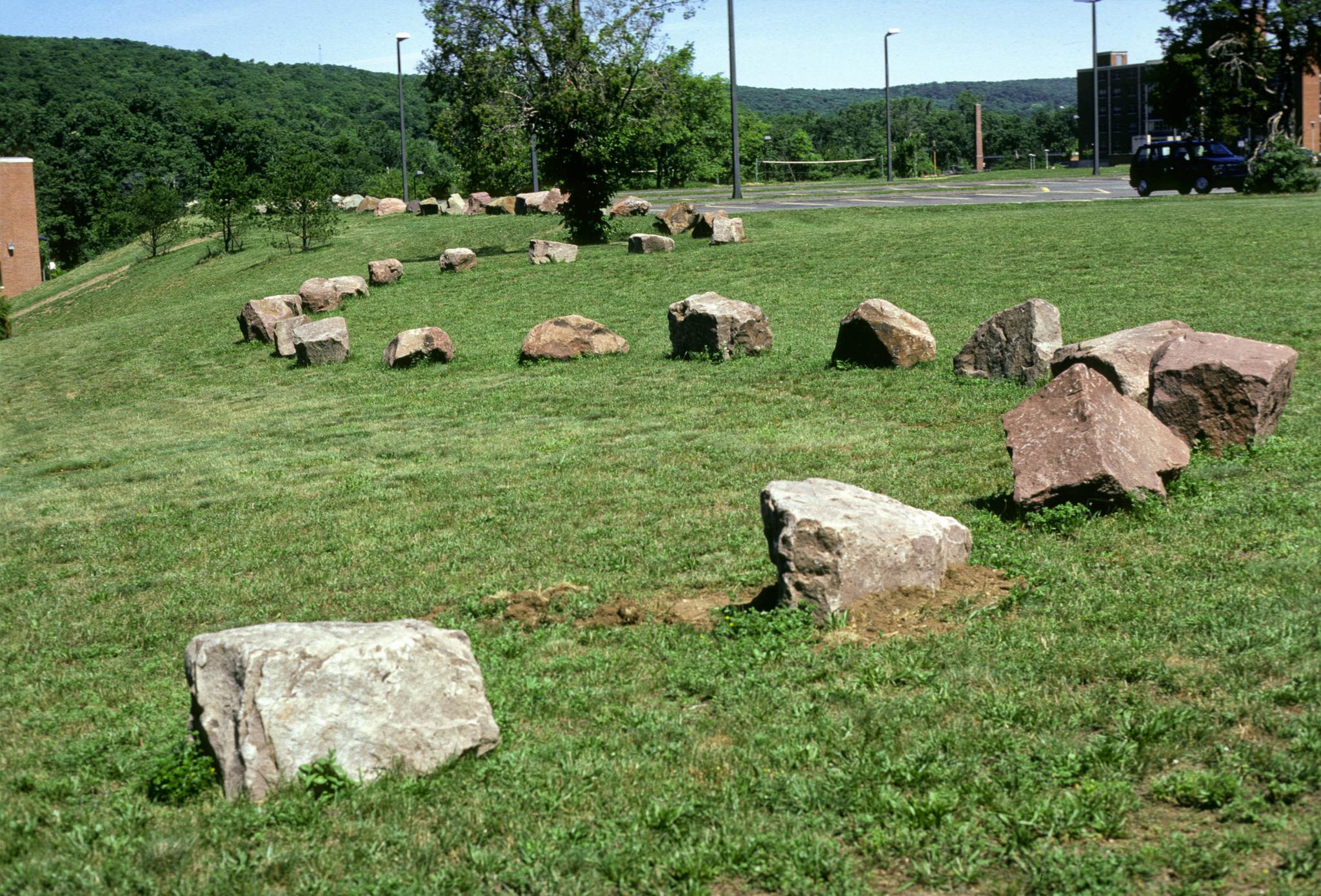 a sculpture made of a curved stone wall with a viewing circle within it