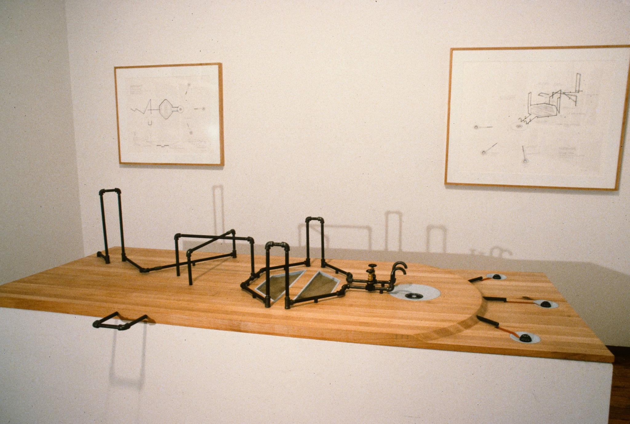 an exhibition showing drawings and a model of a sculpture made of water piping