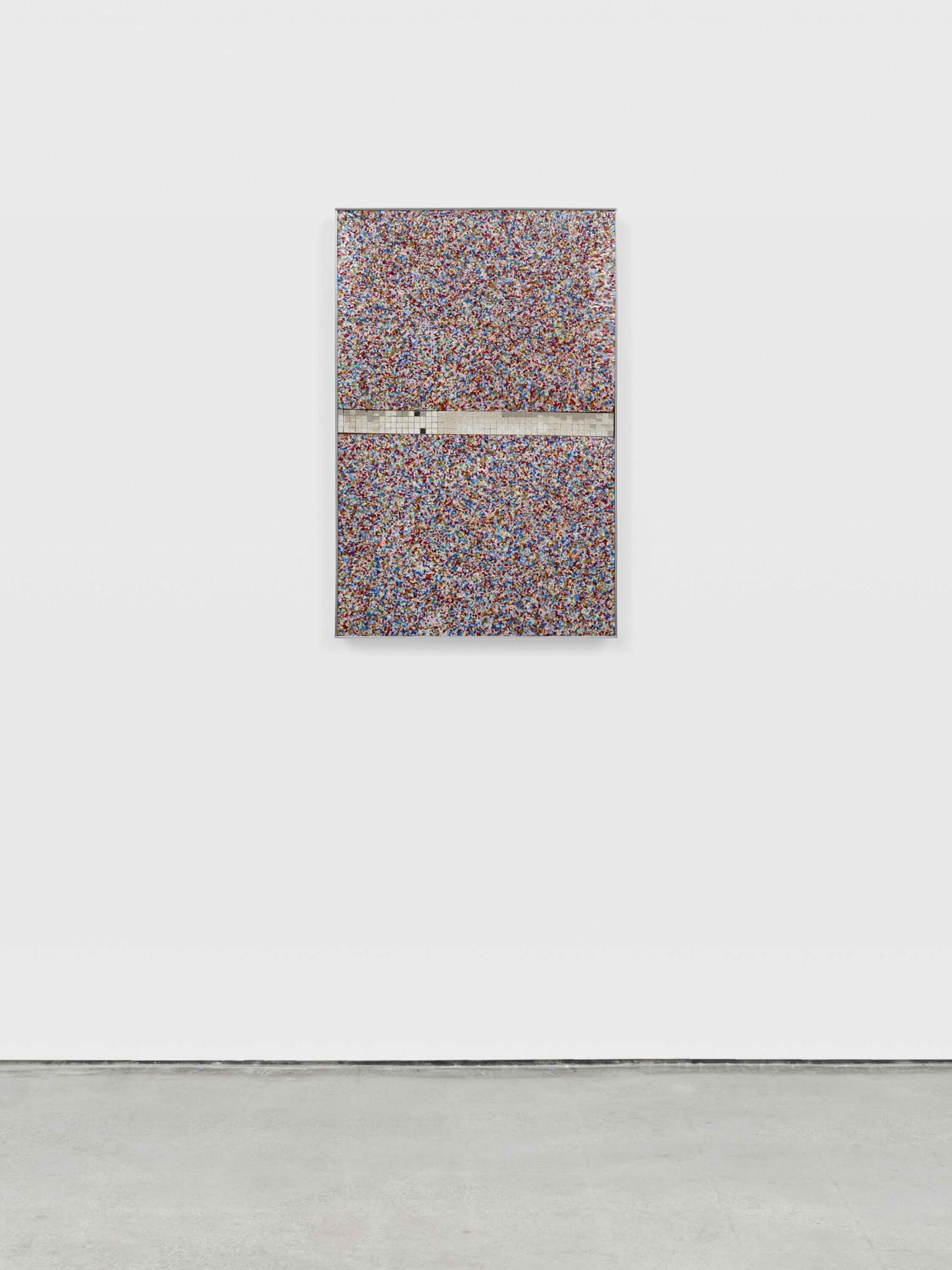 a wall based sculpture made of  brightly colored Plexiglas fragments and mirror tiles