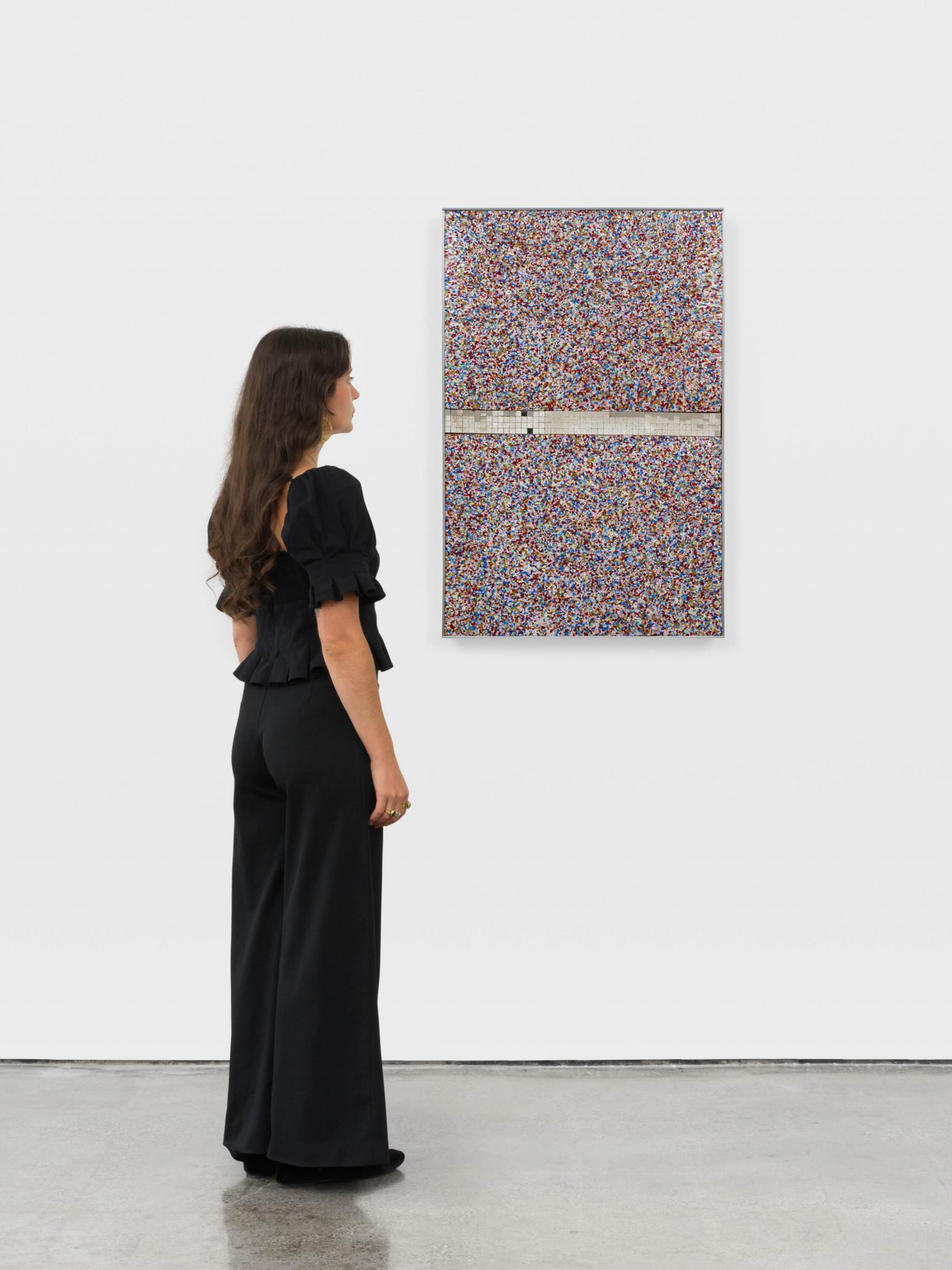 a person looking at a wall based sculpture made of  brightly colored Plexiglas fragments and mirror tiles